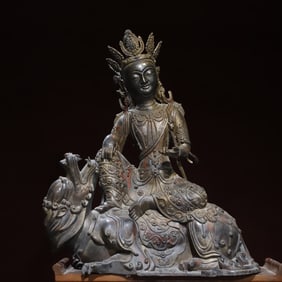 A bronze statue of a Bodhisattva sitting on a gold throne