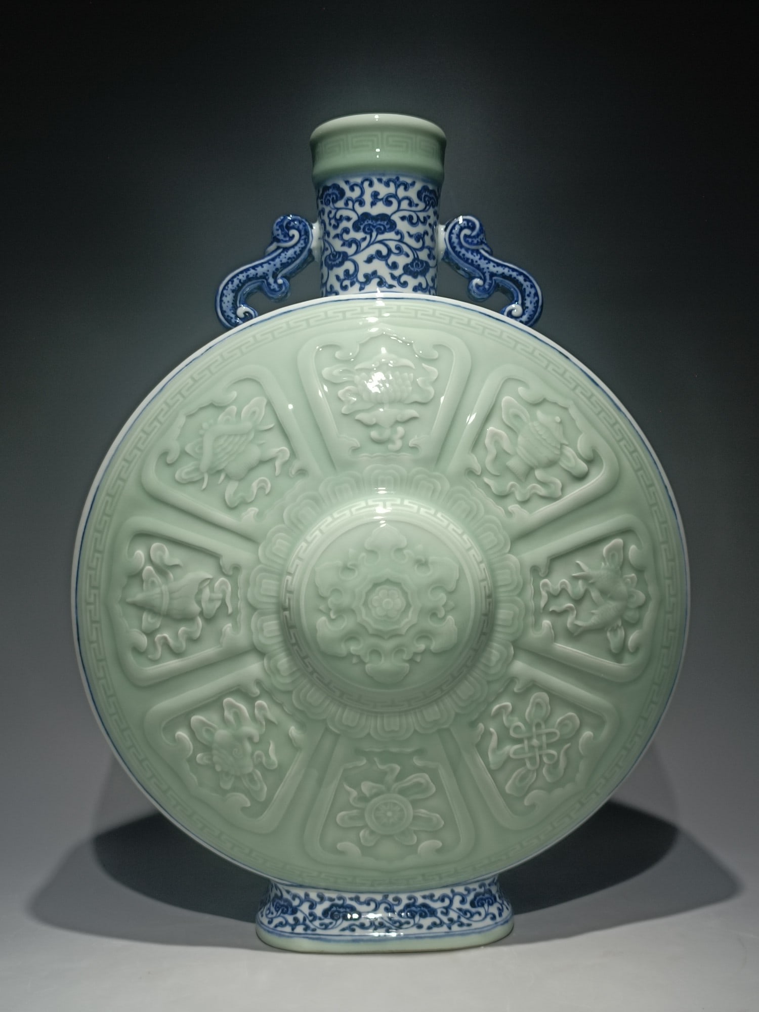 A Qing Dynasty Qianlong blue and white entwined lotus bean celadon glaze secretly engraved with: Qing Qianlong style blue and white entwined lotus bean blue glaze secretly engraved eight treasure pattern amphora moon bottle Size:H:49cm W:36cm (The Dimensions Of All Batches Are Manually Measured.I