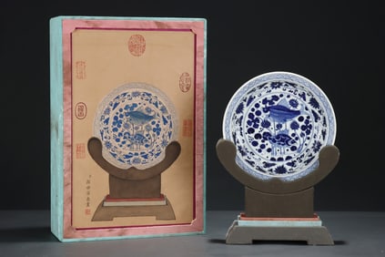 A blue and white plate with a blue and white pattern of entwined lotus fish and algae pattern in the