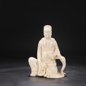 A seated statue of Emperor Wenchang holding a scripture in a Dehua kiln ivory yellow glaze in the