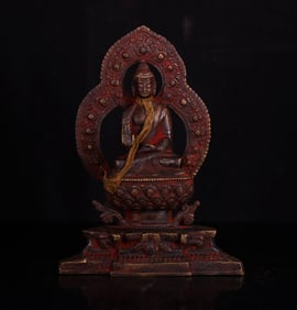 A piece of cinnabar from the Qing Dynasty is offered to the bronze Buddha