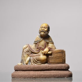 A seated statue of an Arhat holding a sutra painted with gold painted on Shoushan stone