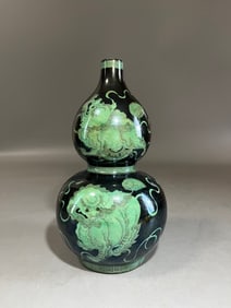 A Qing Qianlong ink green lion rolling hydrangea gourd bottle