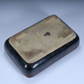 A Qing Dynasty jade imitation Taihu Lake stone ornament with a red base.