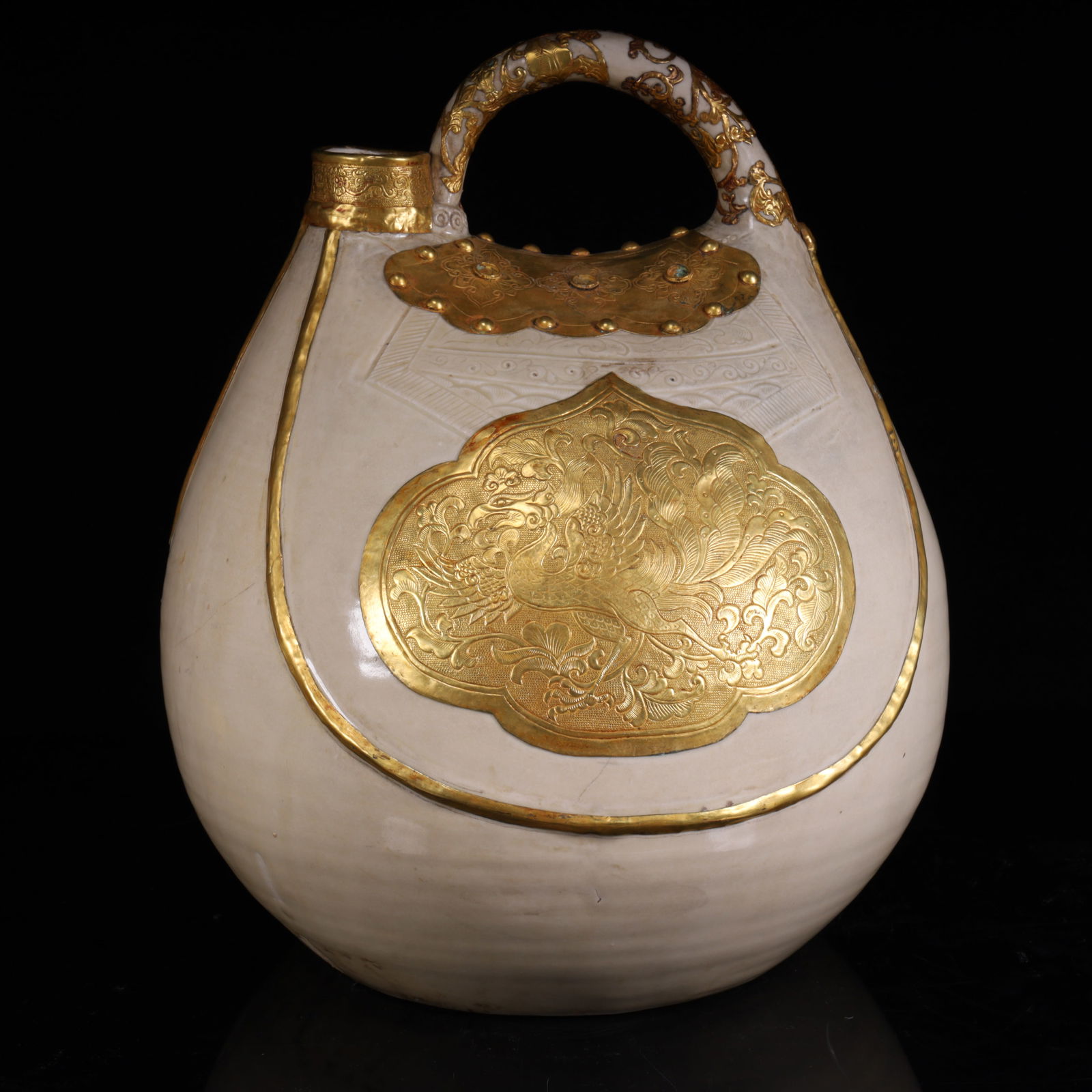 A Tang Dynasty white-glazed gilt leather pot: The white glazed ceramic texture inlaid with gilt decorative pieces (decorated with phoenix bird pattern) and the gilt decoration of the beams are also gilded decorations in the Tang Dynasty, which is