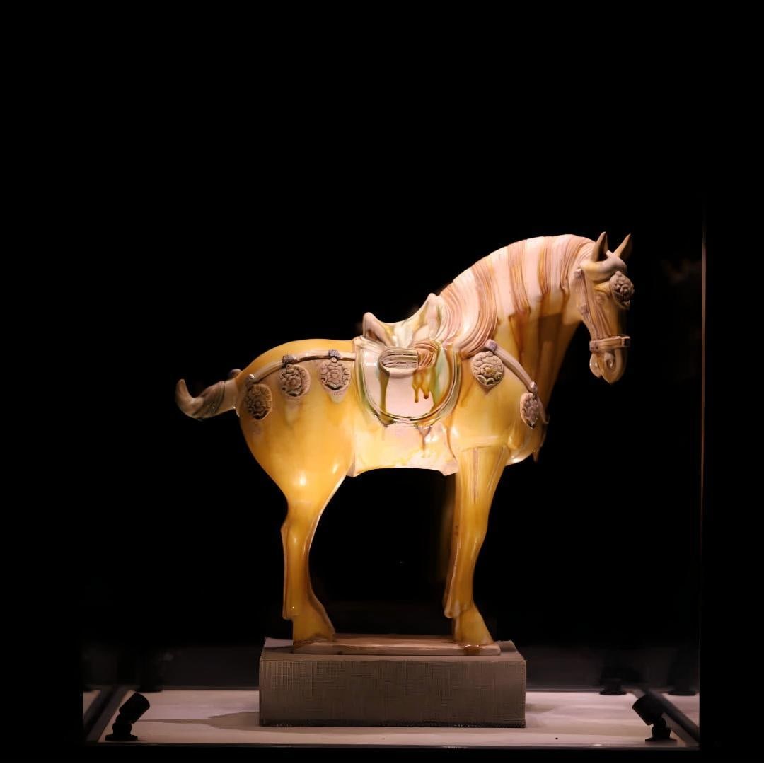 A Tang Dynasty three-color yellow glazed horse figurine: Tang Dynasty Sancai yellow glaze horse figurines are made of kaolin as a tire Fired using Tang Sancai's classic low-temperature lead glaze process The whole body of the horse figurines is mainly yello