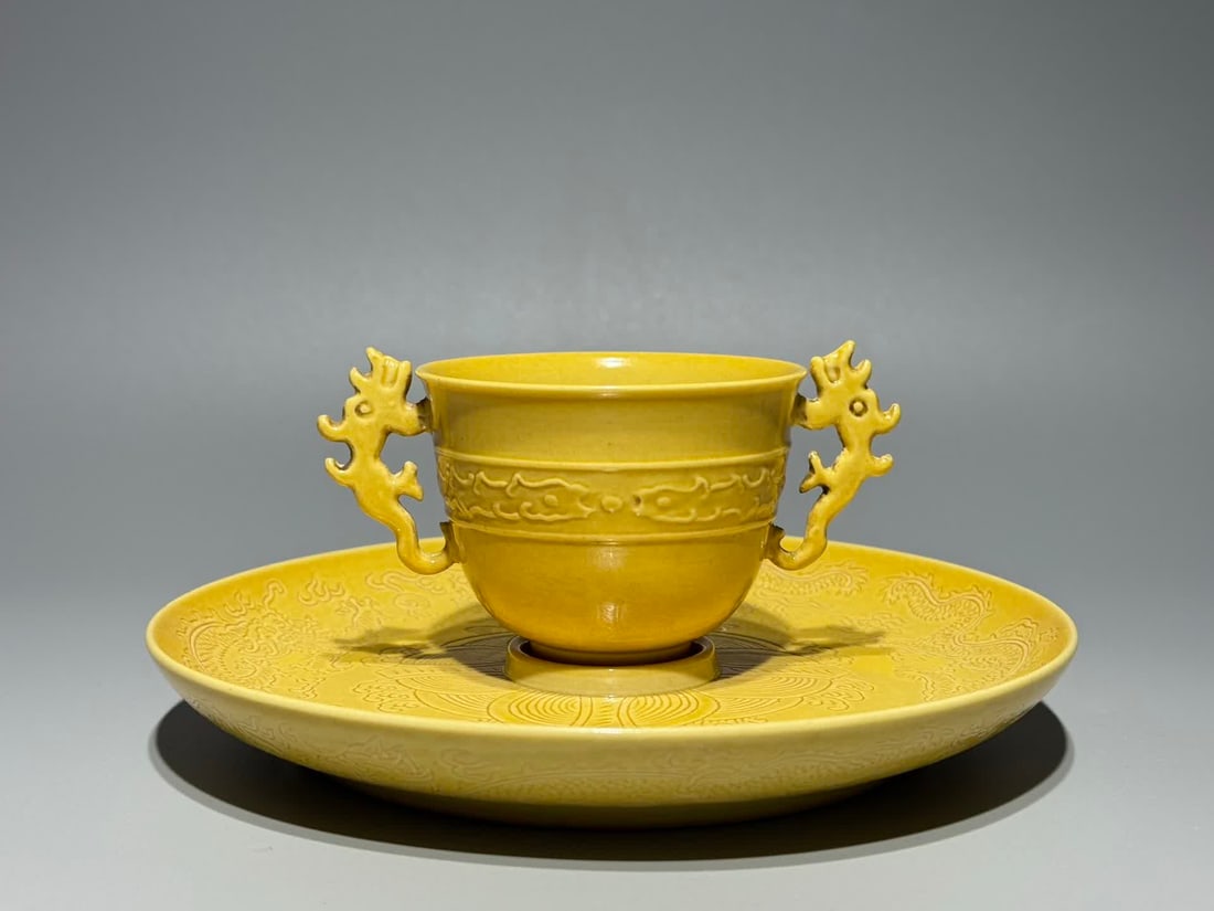 A Qing Dynasty Kangxi year delicate yellow glaze secretly engraved dragon pattern merit cup: The Kangxi Dynasty of the Qing Dynasty made a delicate yellow glaze with dark engraved dragon pattern merit cup SIZE: H: 6.5cm Cup H: 5cm Cup mouthD: 6cm Plus ears W: 7.6cm Plate D: 16cm (The Dimensio