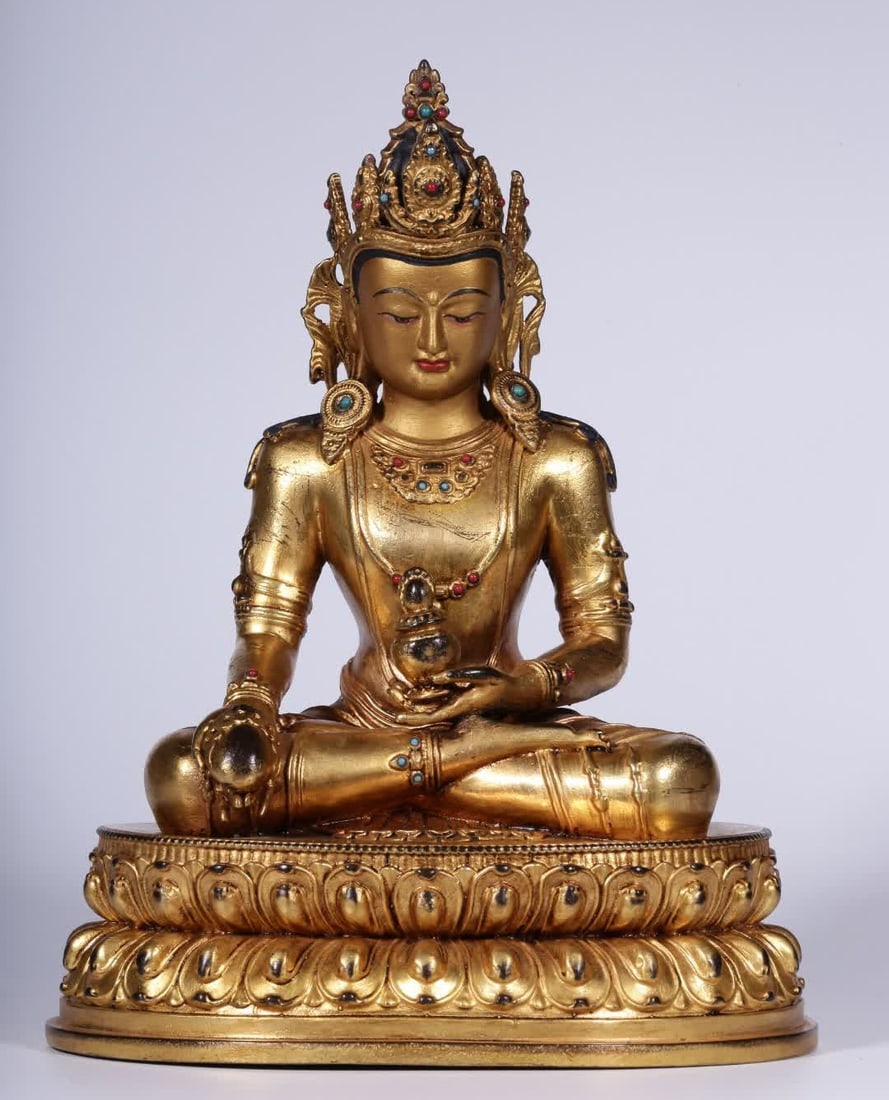 A seated statue of a longevity Buddha in the Qing Dynasty with copper gilt inlaid turquoise agate: Qing Dynasty Copper gilt inlaid turquoise agate longevity Buddha seated statue This longevity Buddha seated statue of copper cast gilt coiled hair into a bun wearing a crown on his head, thin eyes and