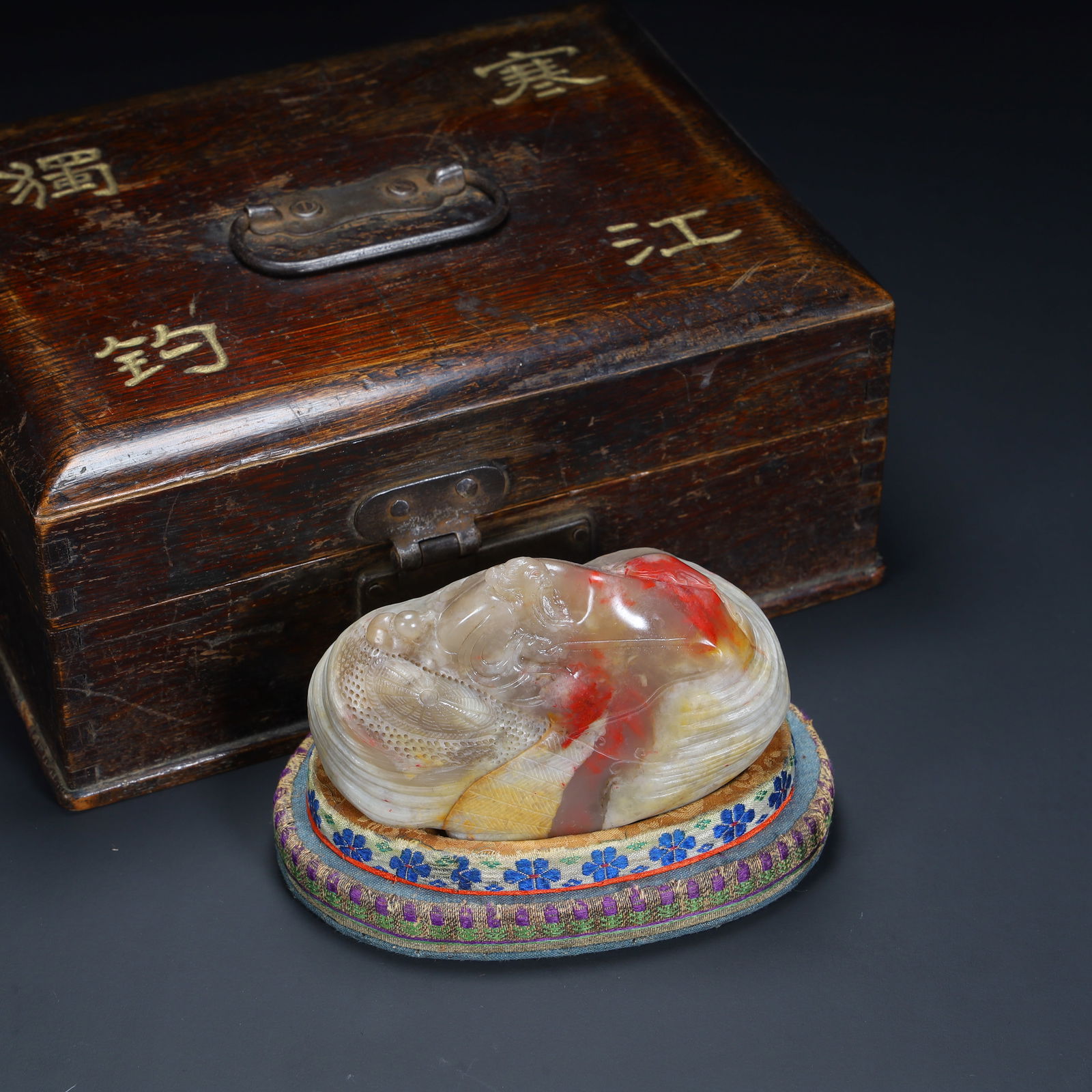 A piece of Qing Dynasty chicken blood stone carving "Hanjiang Fishing Alone" ornament (with wooden: Qing Dynasty Chicken Blood Stone Carving "Cold River Fishing Alone" Ornament (with wooden box) SIZE: H:6.2cm L:9.5cm W:5.5cm W:418.5g (The Dimensions Of All Batches Are Manually Measured.If You Need M