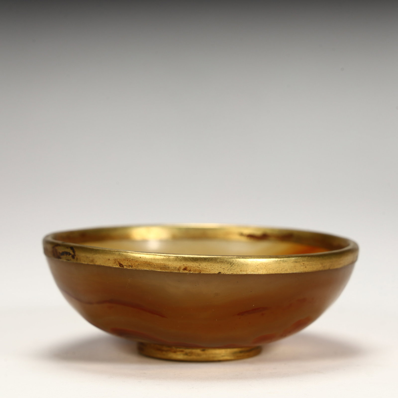 A piece of agate material, the bowl shape is dignified, the mouth edge and bottom foot are gilded,: Agate material, dignified bowl shape, gilded mouth edge and bottom foot, agate color warm, unique texture, reflecting the Tang Dynasty's exquisite skills in combining agate and metal craftsmanship SIZ