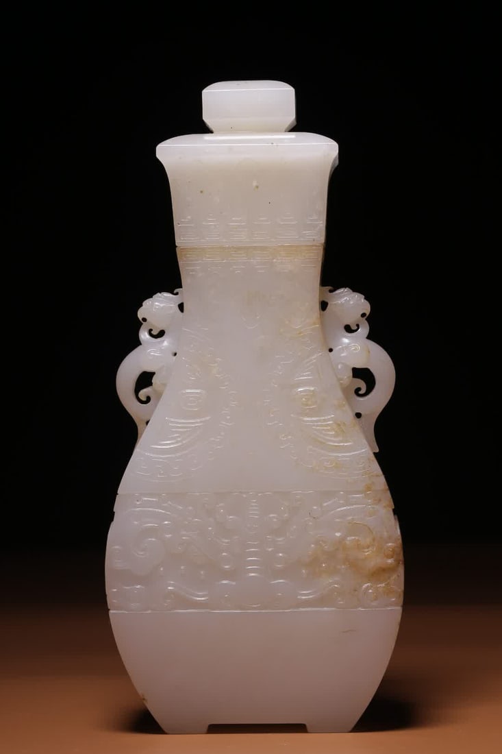 A Qing Dynasty Hetian white jade beast face pattern lid bottle: Made from Hetian white jade, the jade is as delicate as congealed fat, and the texture is fine and warm. The lid bottle is open, the neck is girded, the symmetrical double dragon ears are carved with
