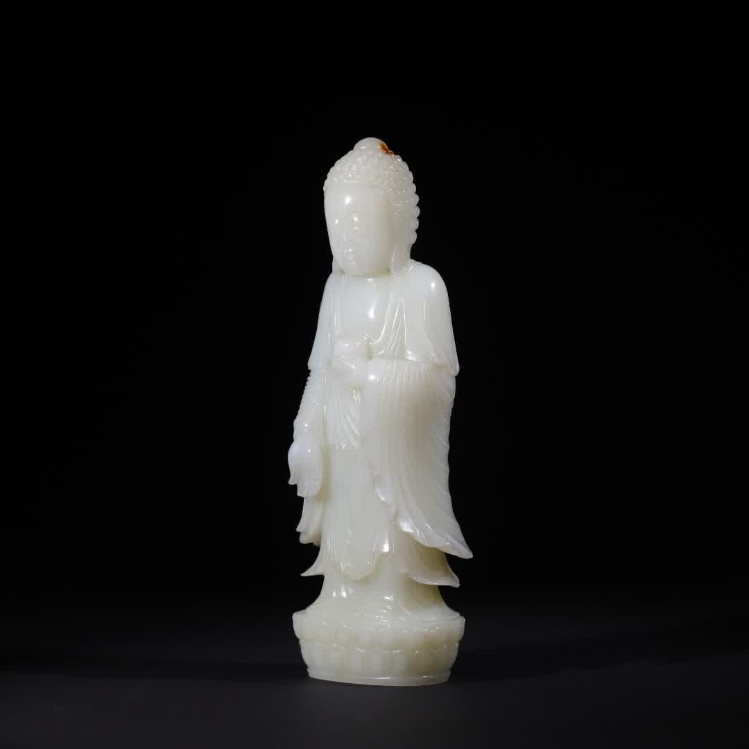 A statue of Shakyamuni Buddha in Hetian jade in the Qing Dynasty: The statue of Shakyamuni Buddha in Hetian Dynasty is carved from Hetian white jade, the jade is warm and delicate, the oil is lustrous and glossy, and the local area has a natural jujube red skin colo