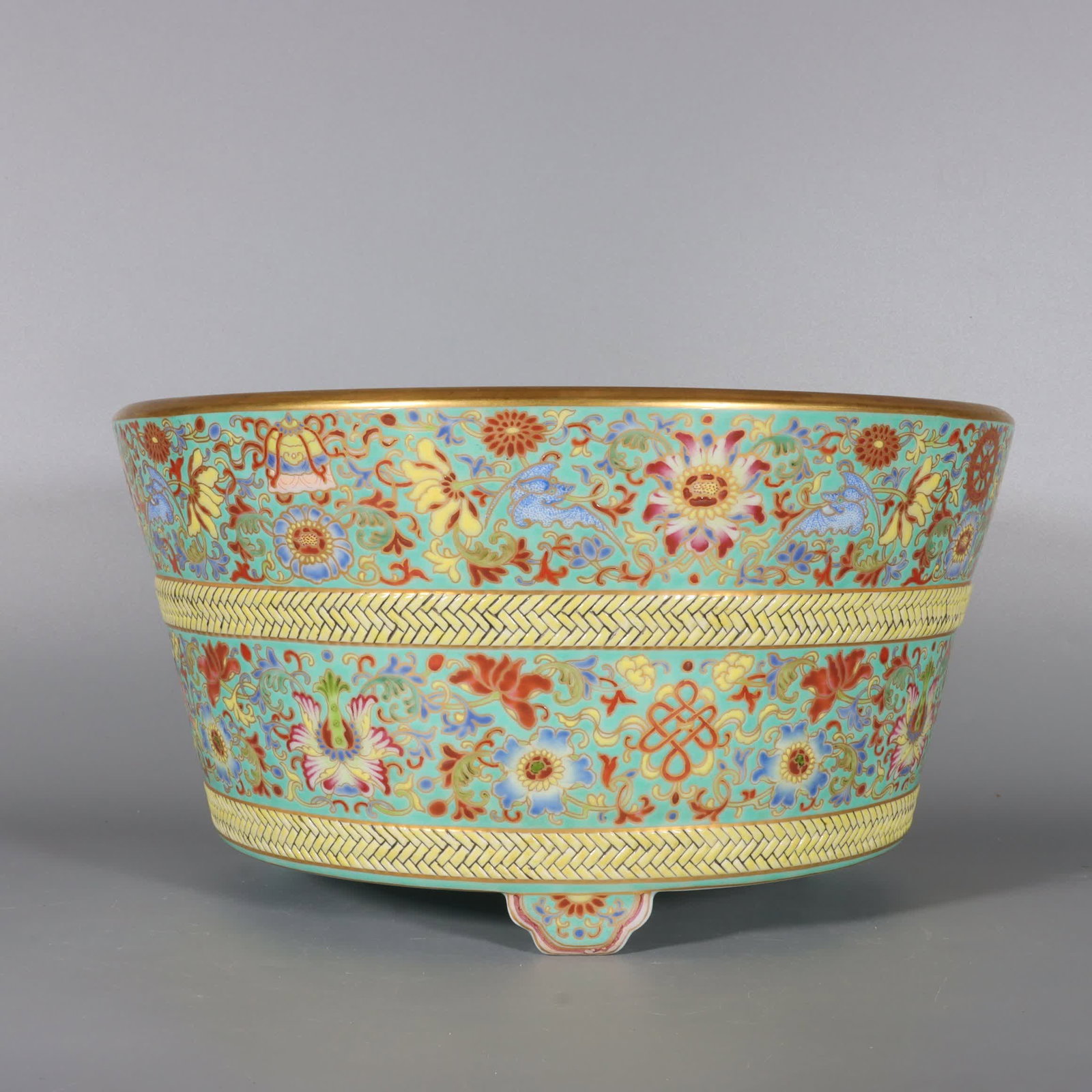 A Qing Dynasty Qianlong period enamel and green ground with gold-painted entwined lotus three-legged: Qing Dynasty Qianlong period enamel green background with gold-painted entwined lotus three-legged treasure basin SIZE: H:16.5cm, Mouth D:30.8cm, Base diameter: 23.5cm (The Dimensions Of All Batches A