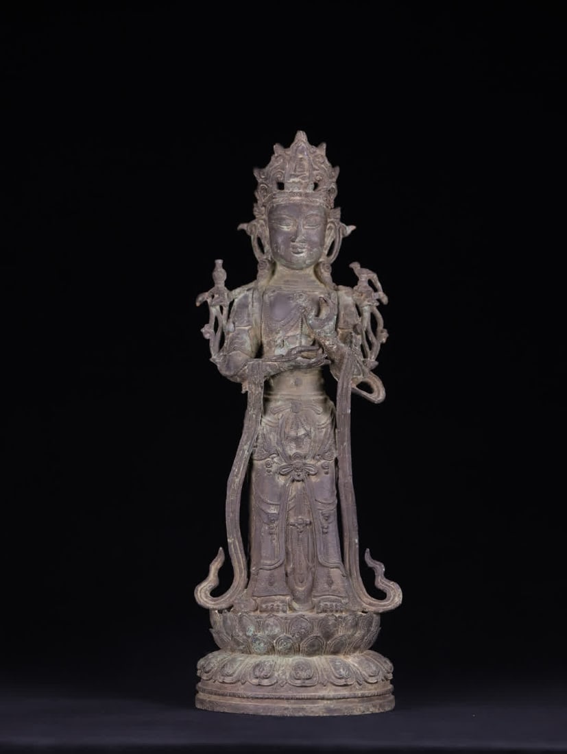 A Ming Dynasty bronze upright Guanyin statue: Ming Dynasty Bronze Standing Guanyin Statue The statue is depicted in a standing pose, adorned with intricate necklaces and celestial garments. The lines of the garments are smooth and delicate, using