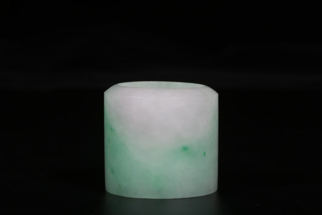 A Qing Dynasty jadeite thumb ring: Qing Dynasty Jadeite Thumb Ring: This finger ring is cylindrical, with a smooth, rounded surface and a smooth, pattern-free surface. Made from jadeite, it has a delicate, smooth texture, transparent