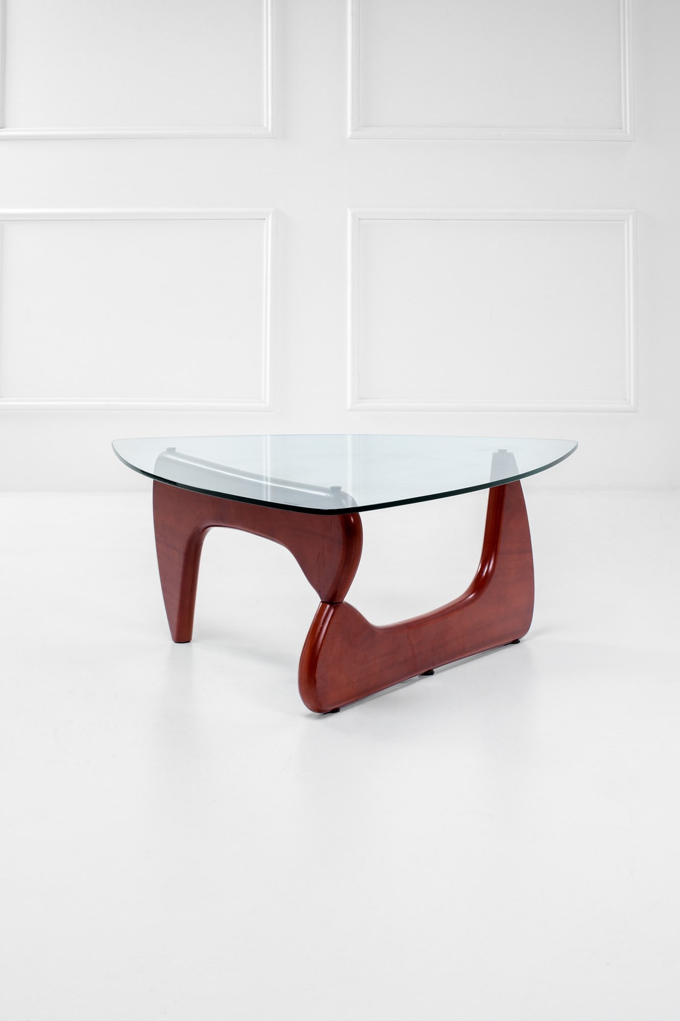 Isamu Noguchi (nello stile di). Tavolo basso: Tavolo bassoLegno verniciato sagomato, cristallo molato.1970 ca.cm 40x108x100