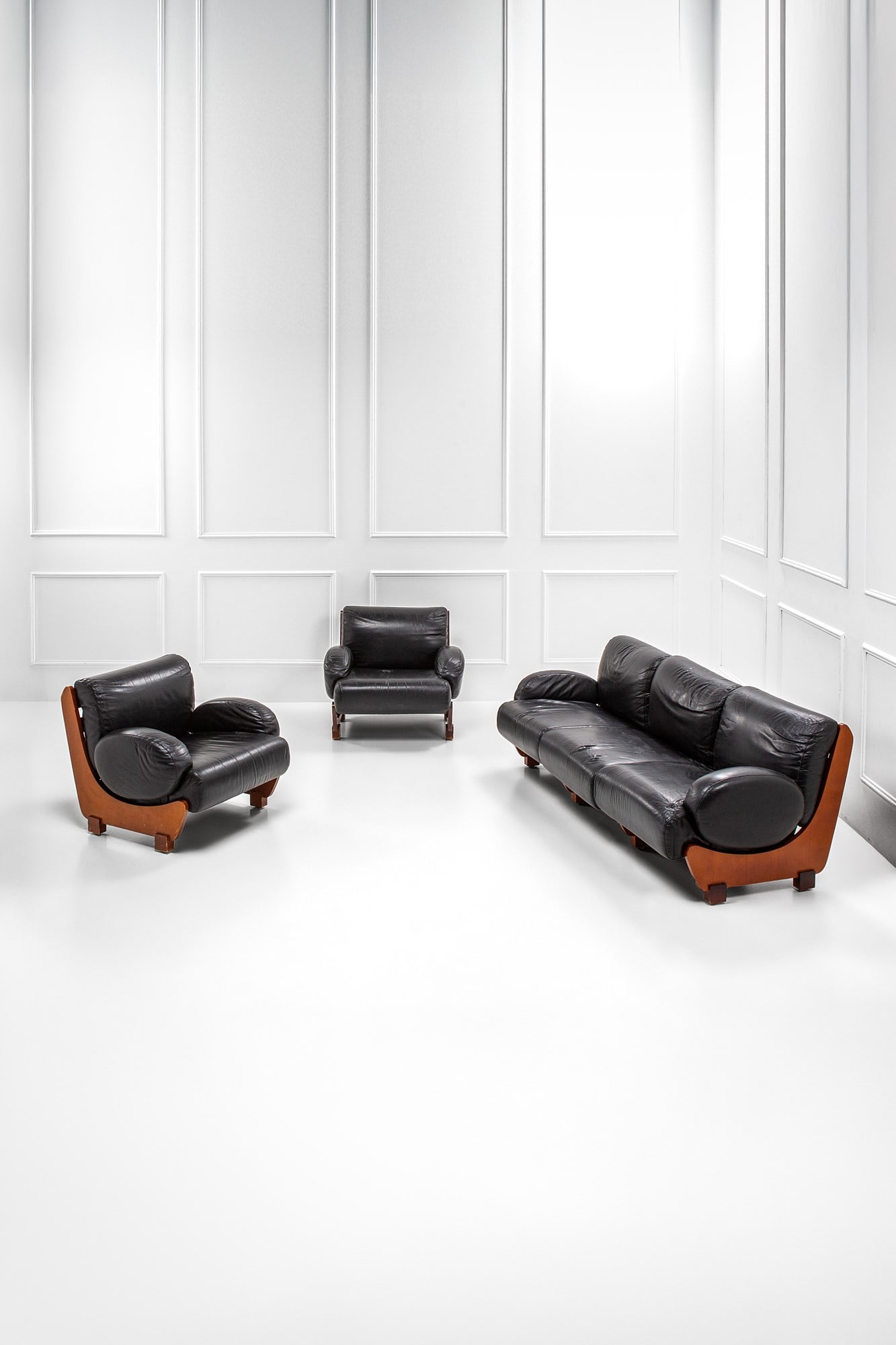 Salotto composto da un divano e due poltrone: Salotto composto da un divano e due poltrone Legno, pelle. 1960 ca. Divano cm 76x220x95, poltrona cm 76x90x95