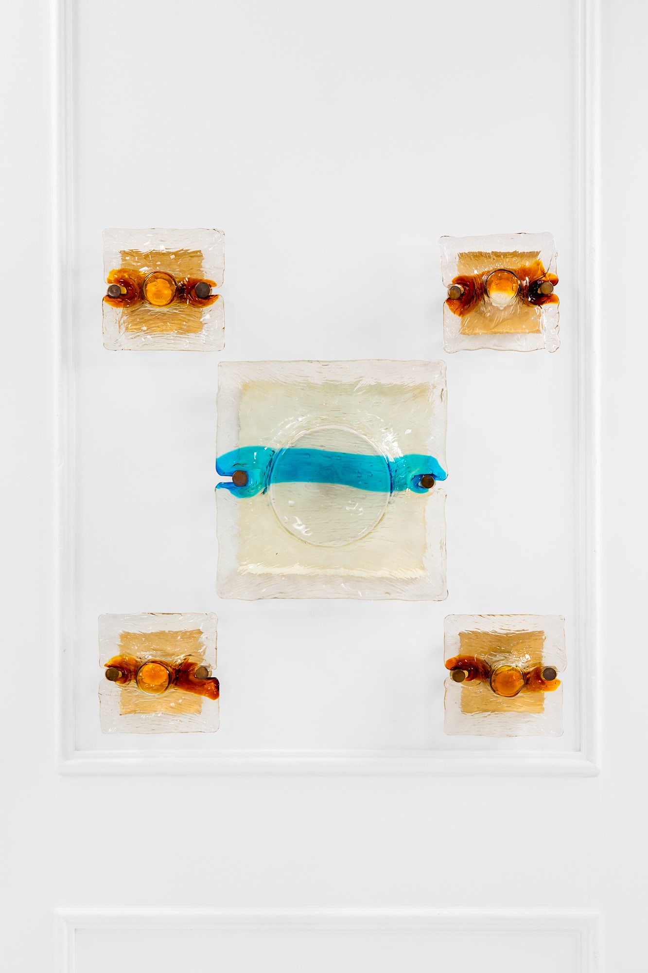 Toni Zuccheri. Cinque lampade da parete mod. Quilt: Cinque lampade da parete mod. Quilt Metallo verniciato, vetro corteccia trasparente con fascia in vetro colorato. Prod. Venini, 1970 ca. Grande cm 43x42x15, piccola cm 22x22x12 Literature: Franco Debo