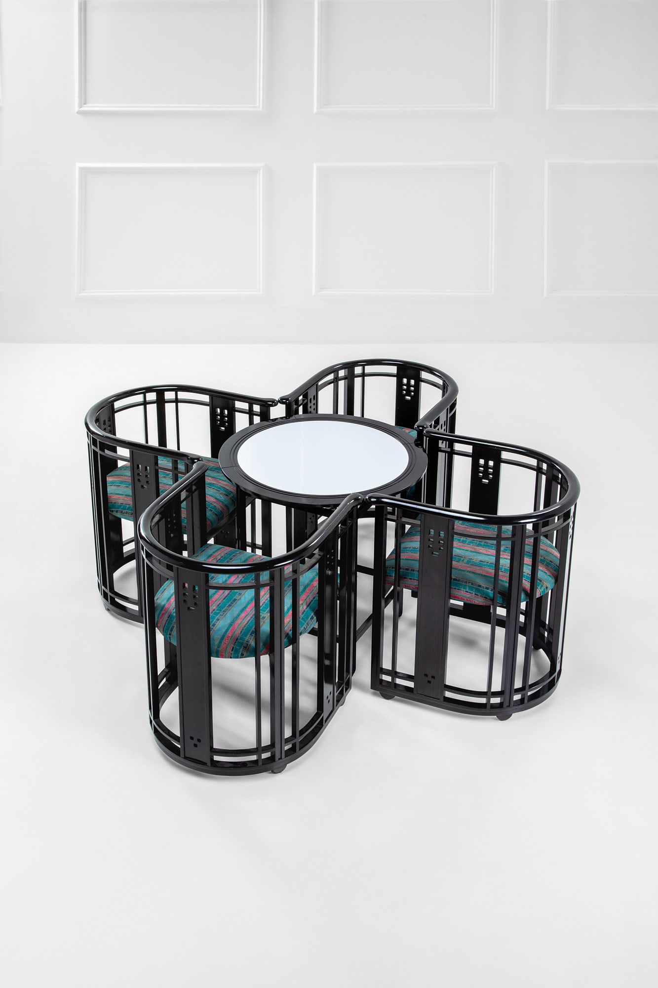 Umberto Asnago. Tavolo e quattro poltrone della serie Chat: Tavolo e quattro poltrone della serie Chat Legno sagomato e curvato laccato nero, tessuto. Prod. Giorgetti, 1980 ca. Marchio del produttore sotto le sedute. Tavolo h cm 63, diam. cm 65, poltrona cm 68