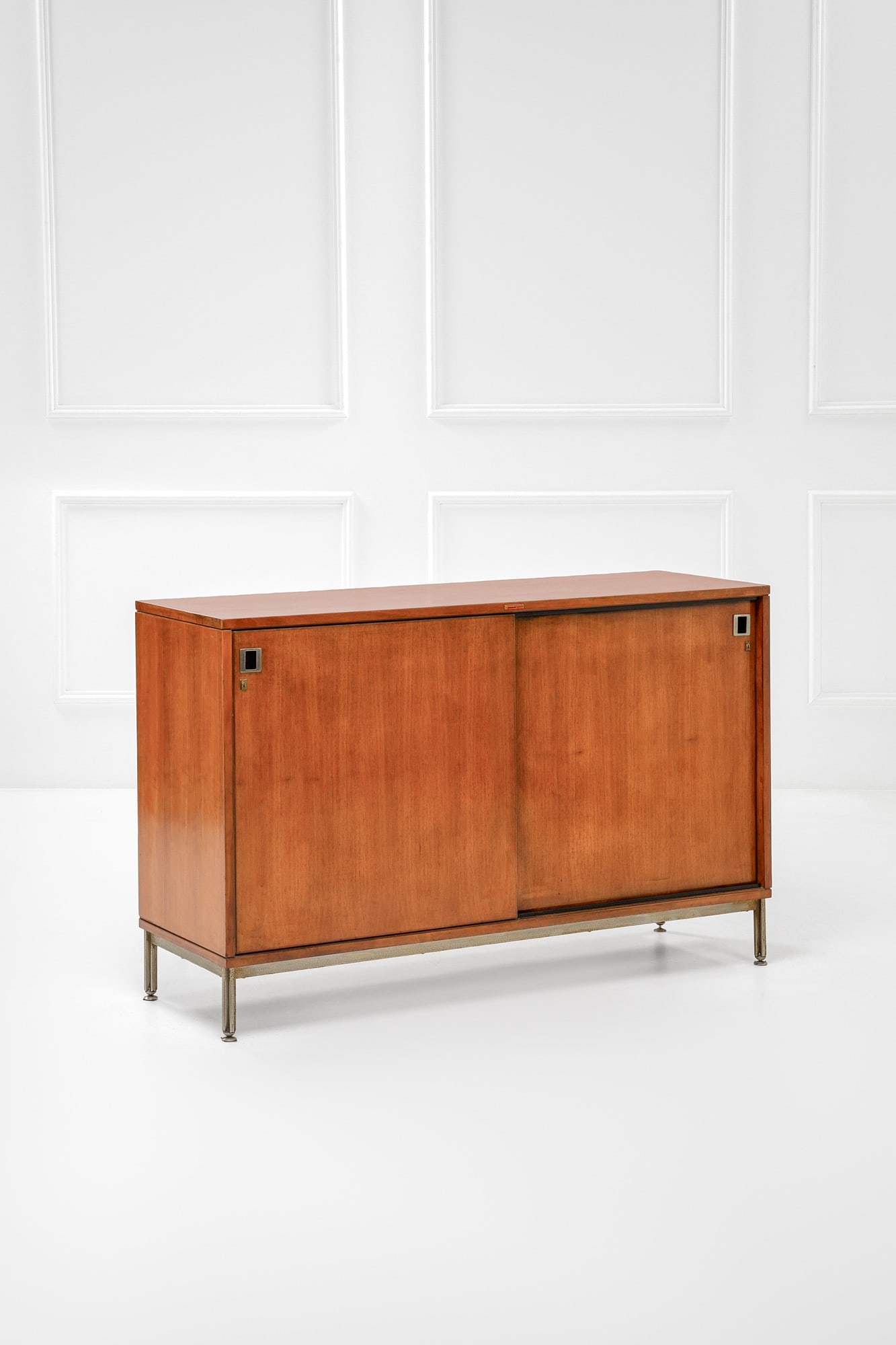 Anonima Castelli. Credenza a due ante: Credenza a due ante Legno impiallacciato, metallo nichelato. Prod. Anonima Castelli, 1960 ca. Etichetta del produttore. cm 90x145x44