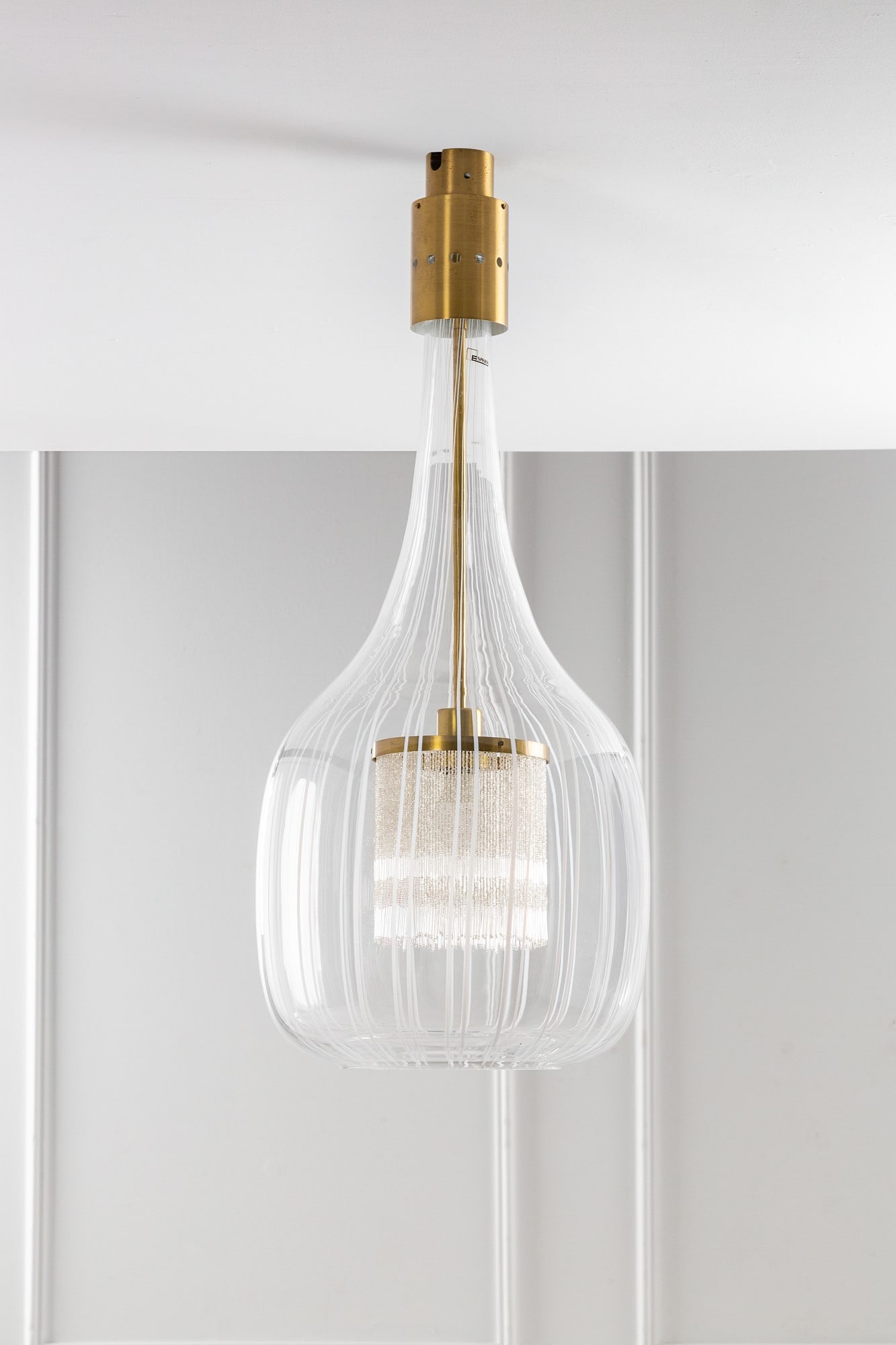 Angelo Brotto. Lampada a sospensione: Lampada a sospensione Vetro soffiato trasparente con canne bianco lattimo, ottone, frangia a perline. Prod. Esperia, 1970 ca. Etichetta del produttore. h cm 92, diam. cm 38