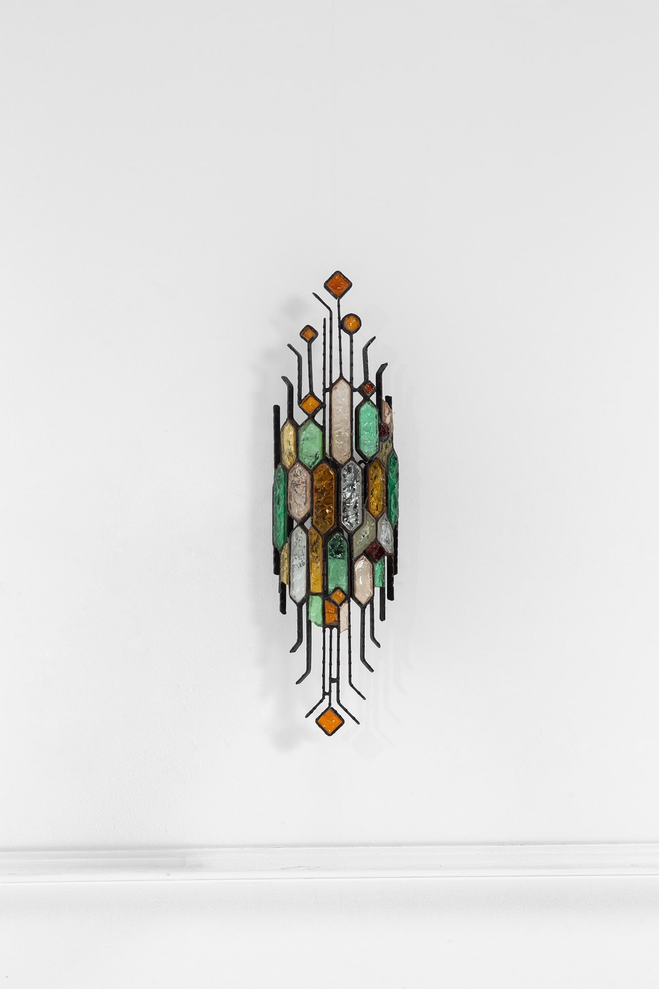 Poliarte. Grande lampada da parete: Grande lampada da parete Metallo brunito, elementi in vetro colorato lavorati a spacco. Prod. Poliarte, 1970 ca. cm 62x17x11