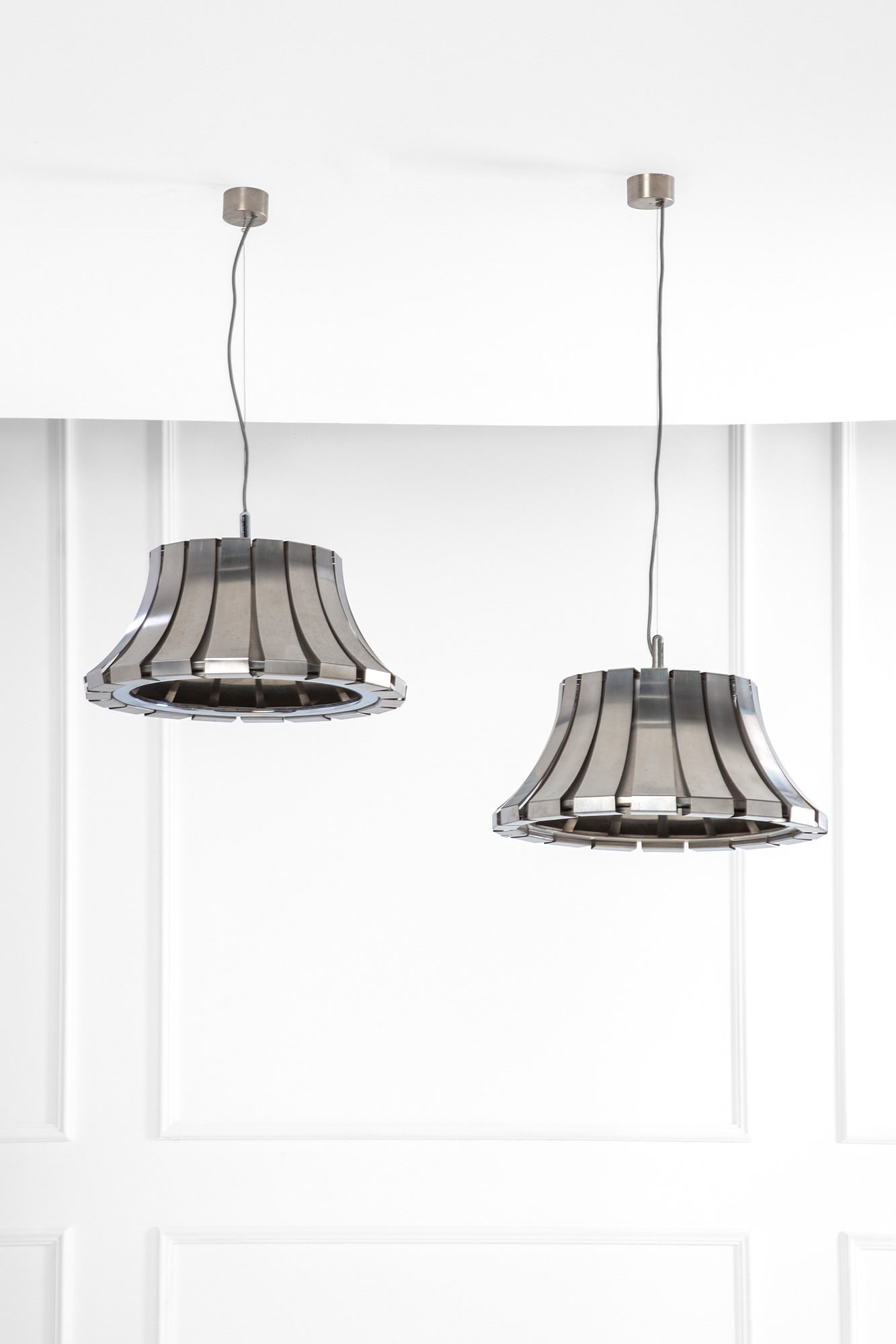 Elio Martinelli. Due lampade a sospensione: Due lampade a sospensione Metallo cromato sagomato. Prod. Martinelli luce, 1970 ca. Etichetta del produttore. h cm 93, diam cm 49, h cm 75, diam. cm 49
