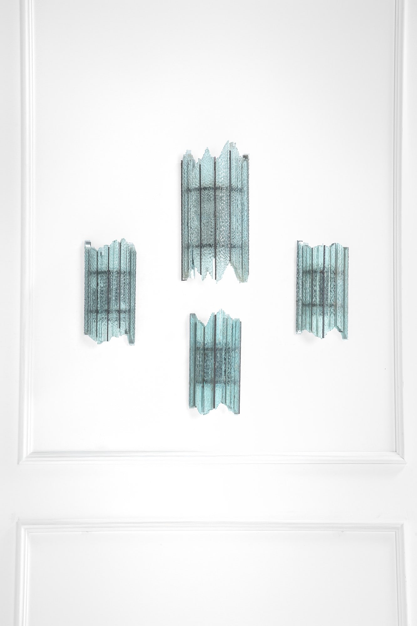 Poliarte. Quattro lampade da parete: Quattro lampade da parete Elementi in vetro di forte spessore lavorati a spacco, metallo verniciato. Prod. Poliarte, 1970 ca. misure differenti, cm 50x25x12, cm 38x18x10, cm 36x19x10