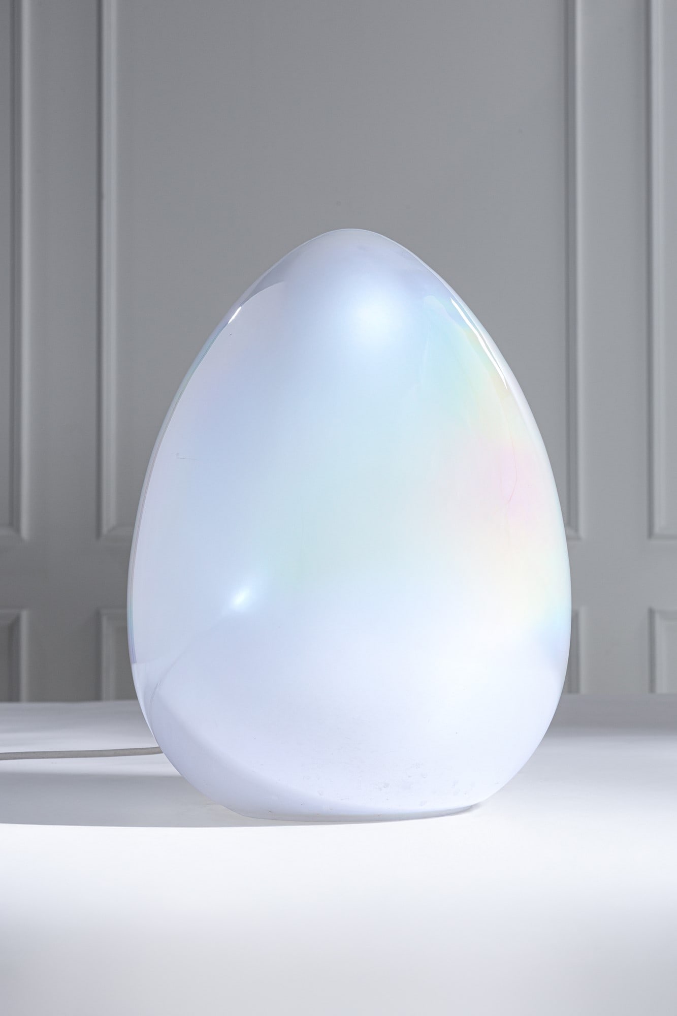 Vetreria artistica Gambaro e Poggi. Lampada da tavolo a forma di uovo: Lampada da tavolo Vetro di Murano lattimo iridato a forma di uovo. Prod. Vetreria Artistica Gambaro & Poggi, 1990 ca. Etichetta di produzione con codice della vetreria. h cm 45, diam. cm 30