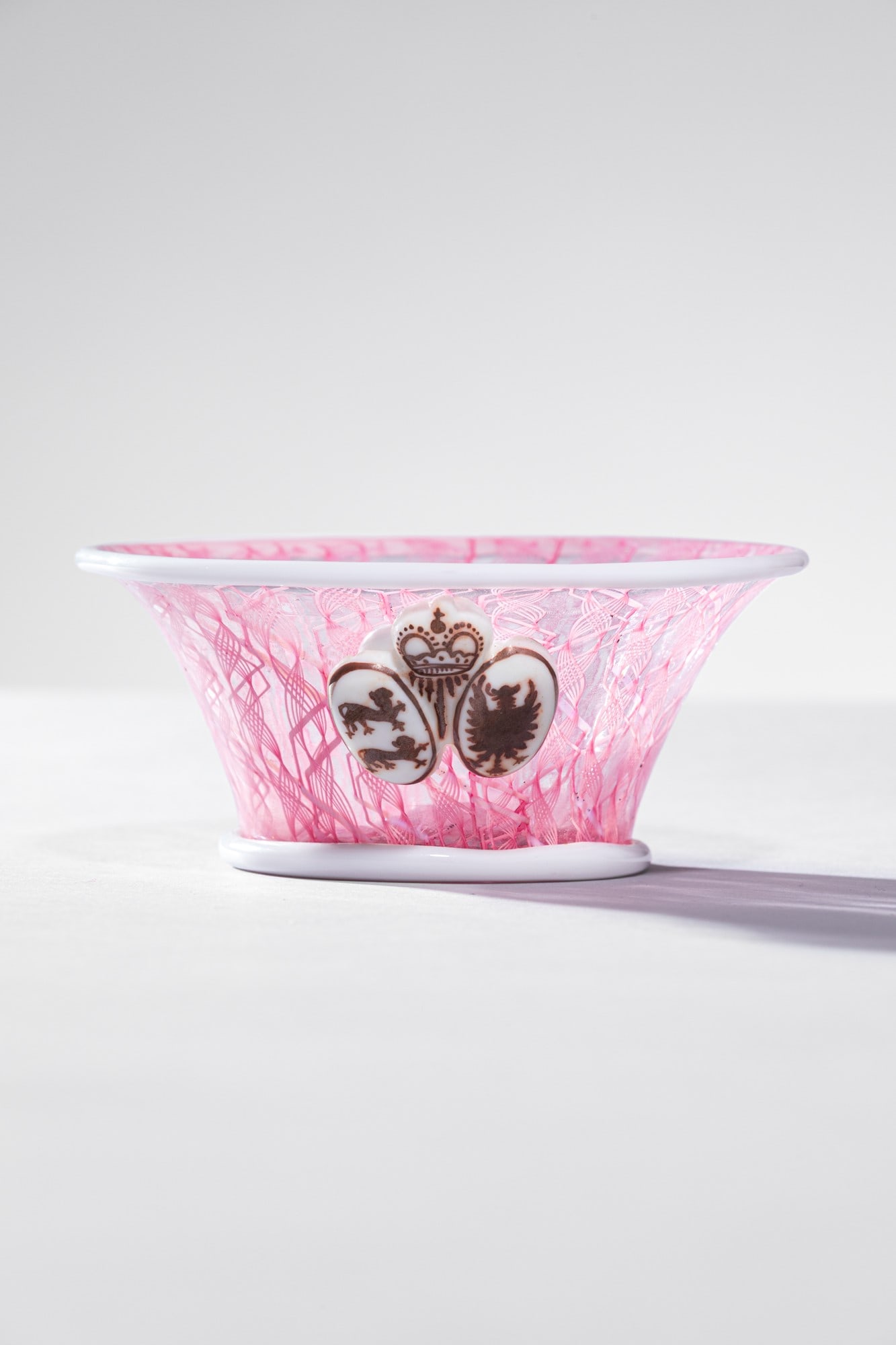 Paolo Venini. Coppa celebrativa: Coppa celebrativa Vetro soffiato zanfirico con applicazioni in vetro lattimo e stemmi decorati in oro. Venini, 1957 ca. Firma all'acido Venini Murano Italia. h cm 5, diam. cm 12 Bibiliografia: Franco