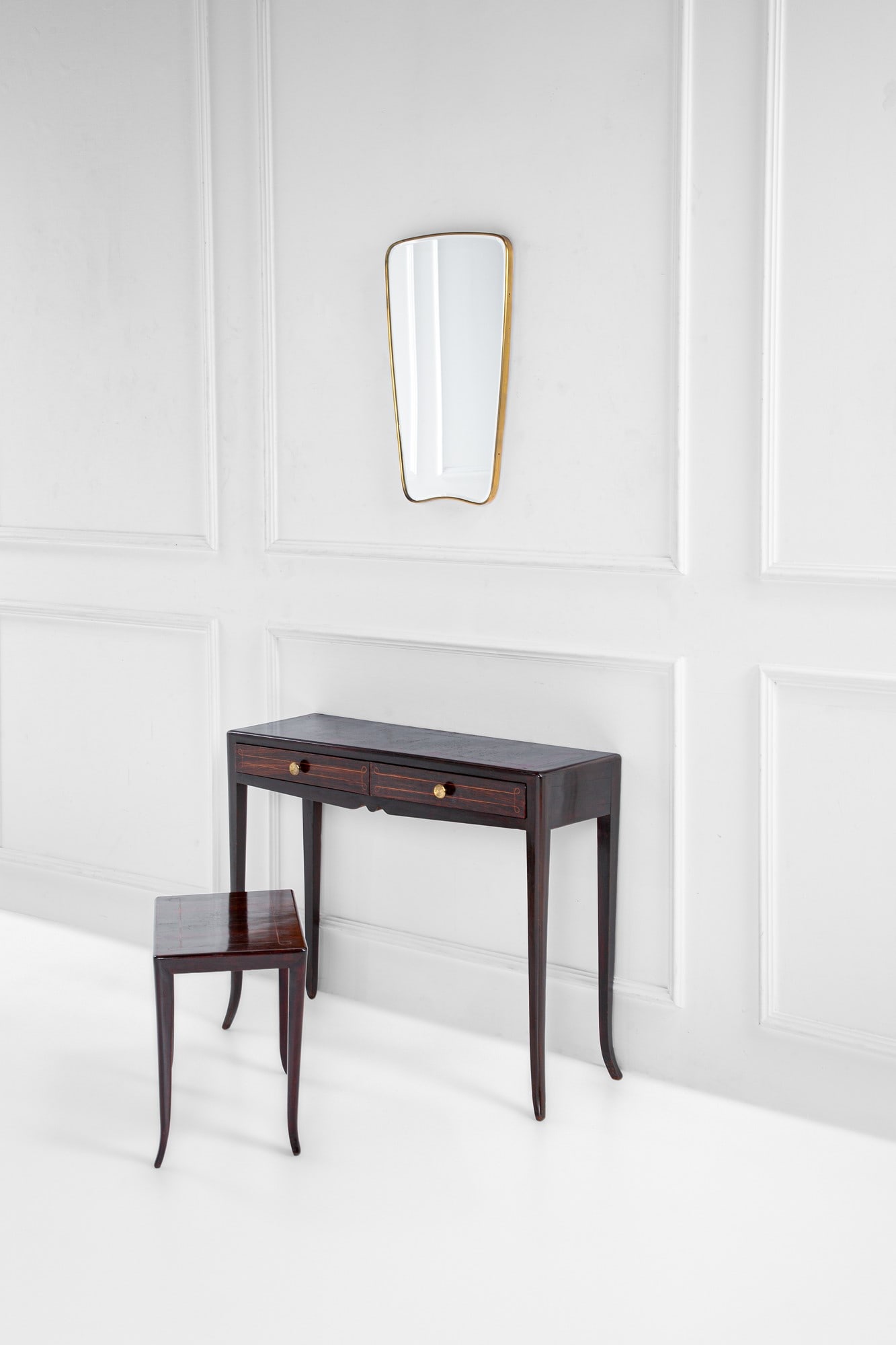 Set composto da console, specchiera e sgabello: Set composto da console, specchiera e sgabelloLegno impiallacciato, ottone, vetro specchiato.1950 ca.Console cm 82x104x37, specchio cm 70x41x3, sgabello cm 47x53x34