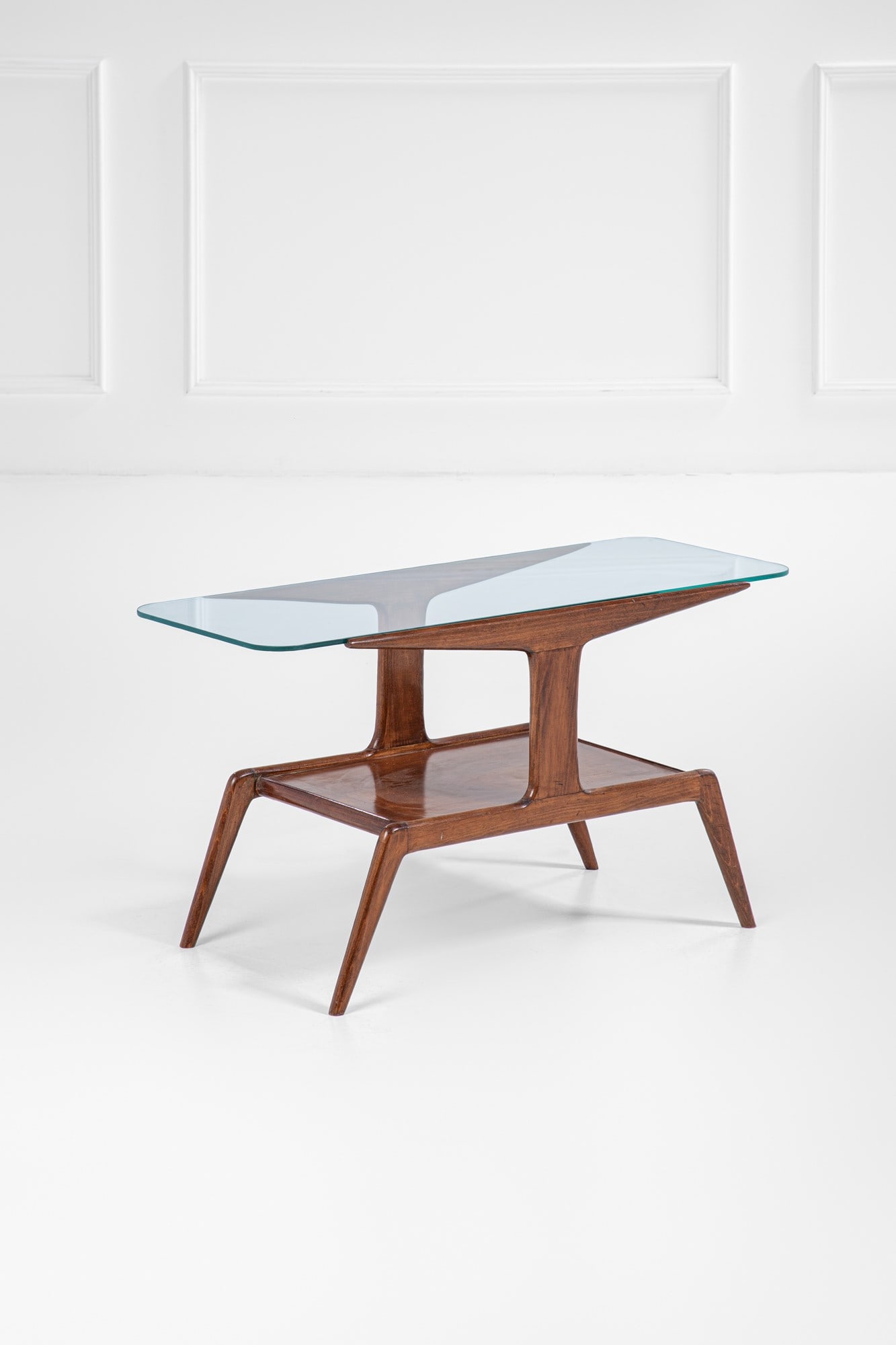 Gio Ponti. Tavolino: Tavolino a due ripiani Legno di frassino tinto, cristallo molato. 1950 ca. cm 52x95x42