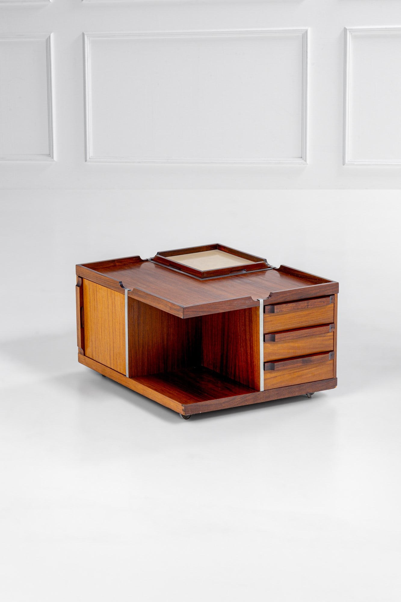 Fiarm. Mobile bar da centro con ruote: Mobile bar da centro con ruoteComposto da vani a giorno, cassetti, vani con ante e vassoio asportabile.Legno impiallacciato, legno massello, metallo cromato, laminato plastico.Prod. Fiarm, 1970 ca.cm