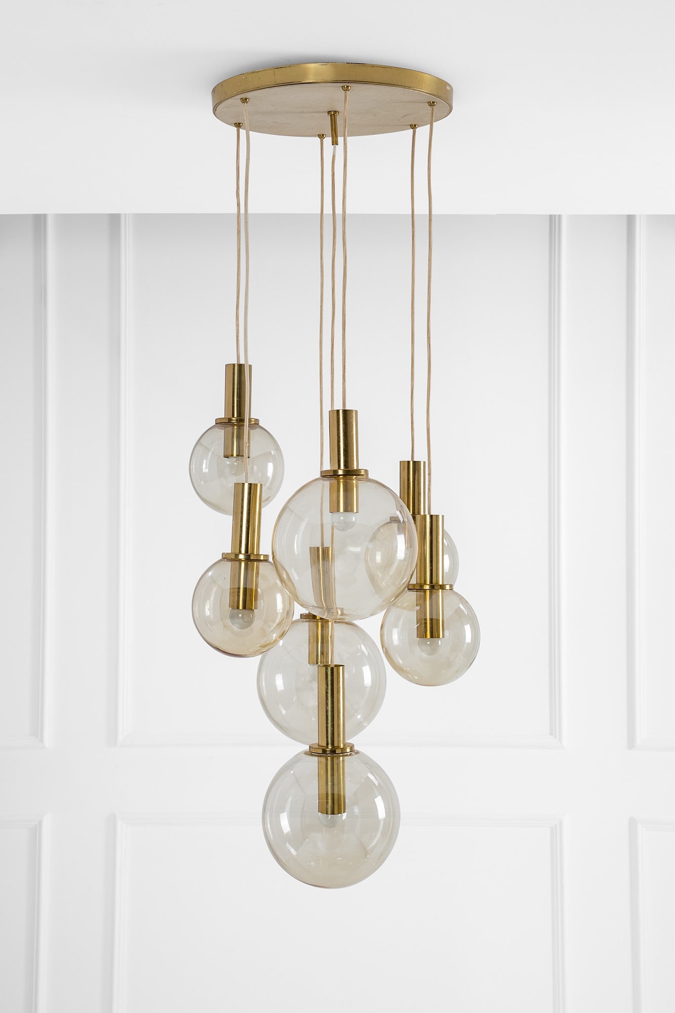 Hans Agne Jakobsson (attr.). Lampada a sospensione a sette globi: Lampada a sospensione a sette globi Vetro trasparente ambra, ottone dorato. 1960 ca. h variabile, ingombro max diam. cm 60