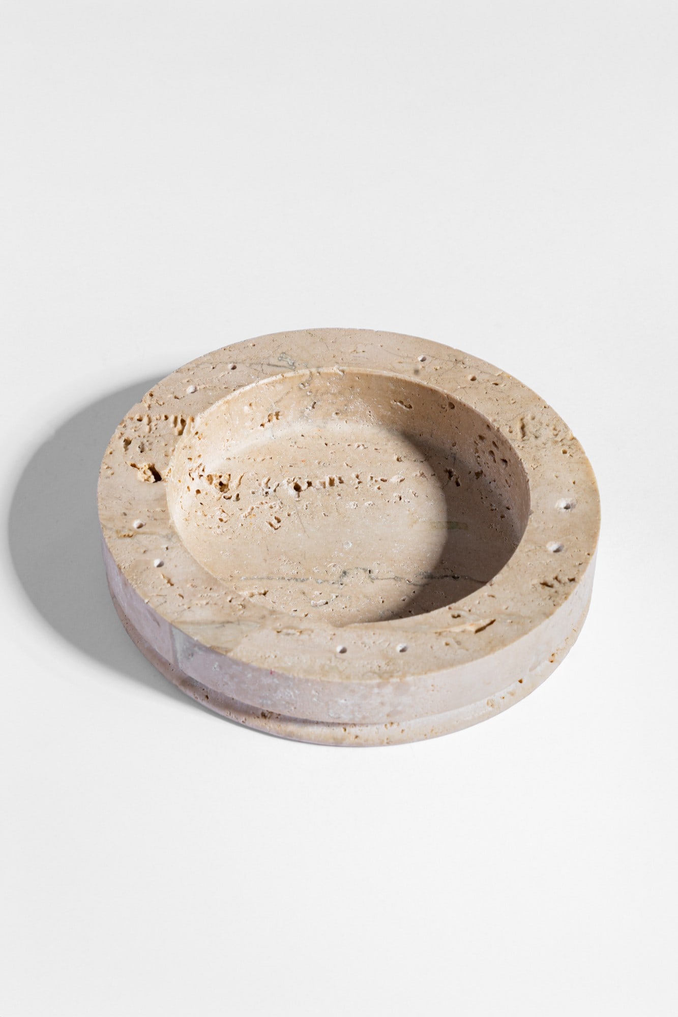 Mattia Pastorino. Gettacarte della serie Forme Contemporanee: Gettacarte della serie Forme ContemporaneeTravertino fresato.Edizioni Cleto Munari, 1980 ca.Etichetta con nome del designer, dell'editore e della serie.h cm 4, diam. cm 18