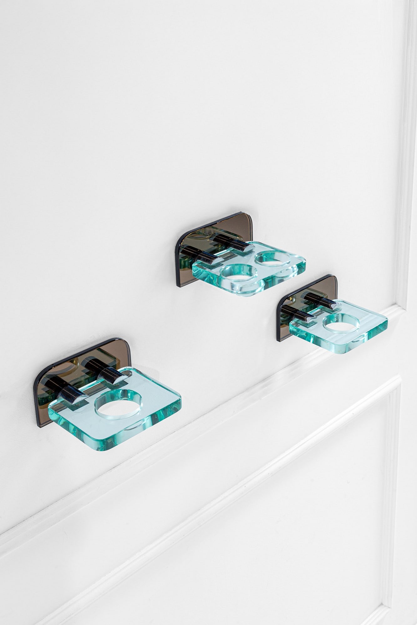 Fontana Arte. Tre portabicchieri da bagno: Tre portabicchieri da bagnoVetro di forte spessore fumé e cristallo, metallo cromato.Prod. Fontana Arte, 1960 ca.cm 11x21x18