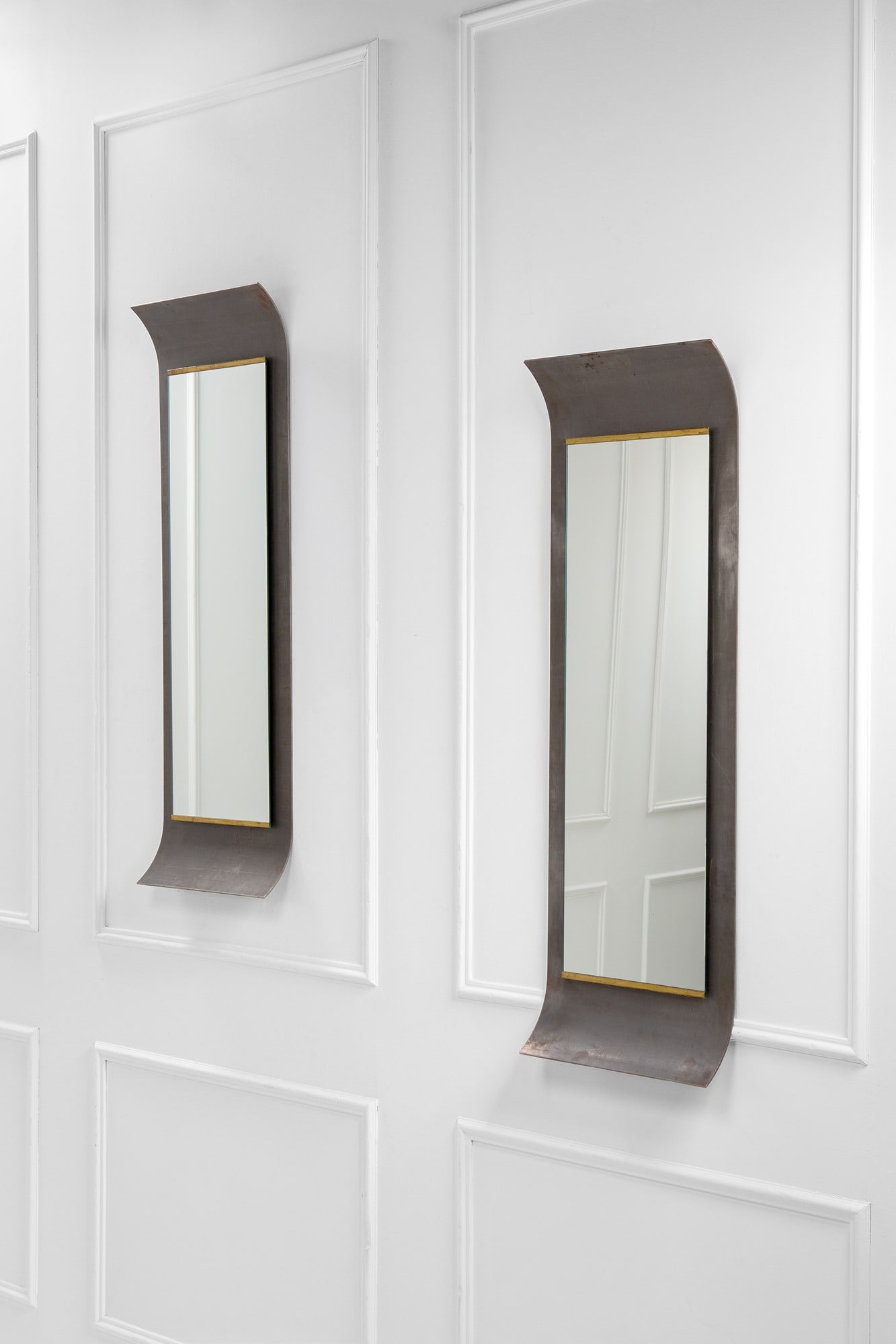 Coppia di specchiere: Coppia di specchiere Metallo ossidato curvato, vetro specchiato, ottone. 1990 ca. cm 135x46x10