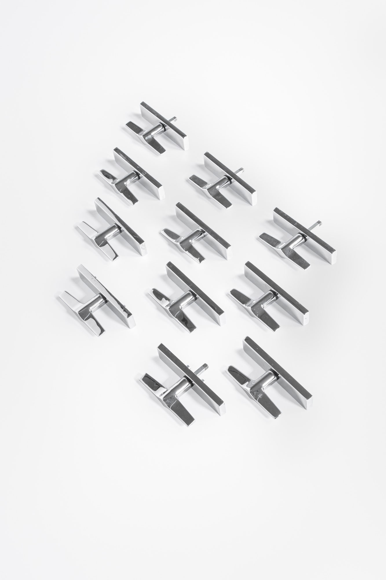 Gio Ponti. Undici maniglie da finestra della serie Lama: Undici maniglie da finestra della serie LamaMetallo cromato.Prod. Olivari dal 1954 ca.Marchio del produttore incusso.cm 14x3x10