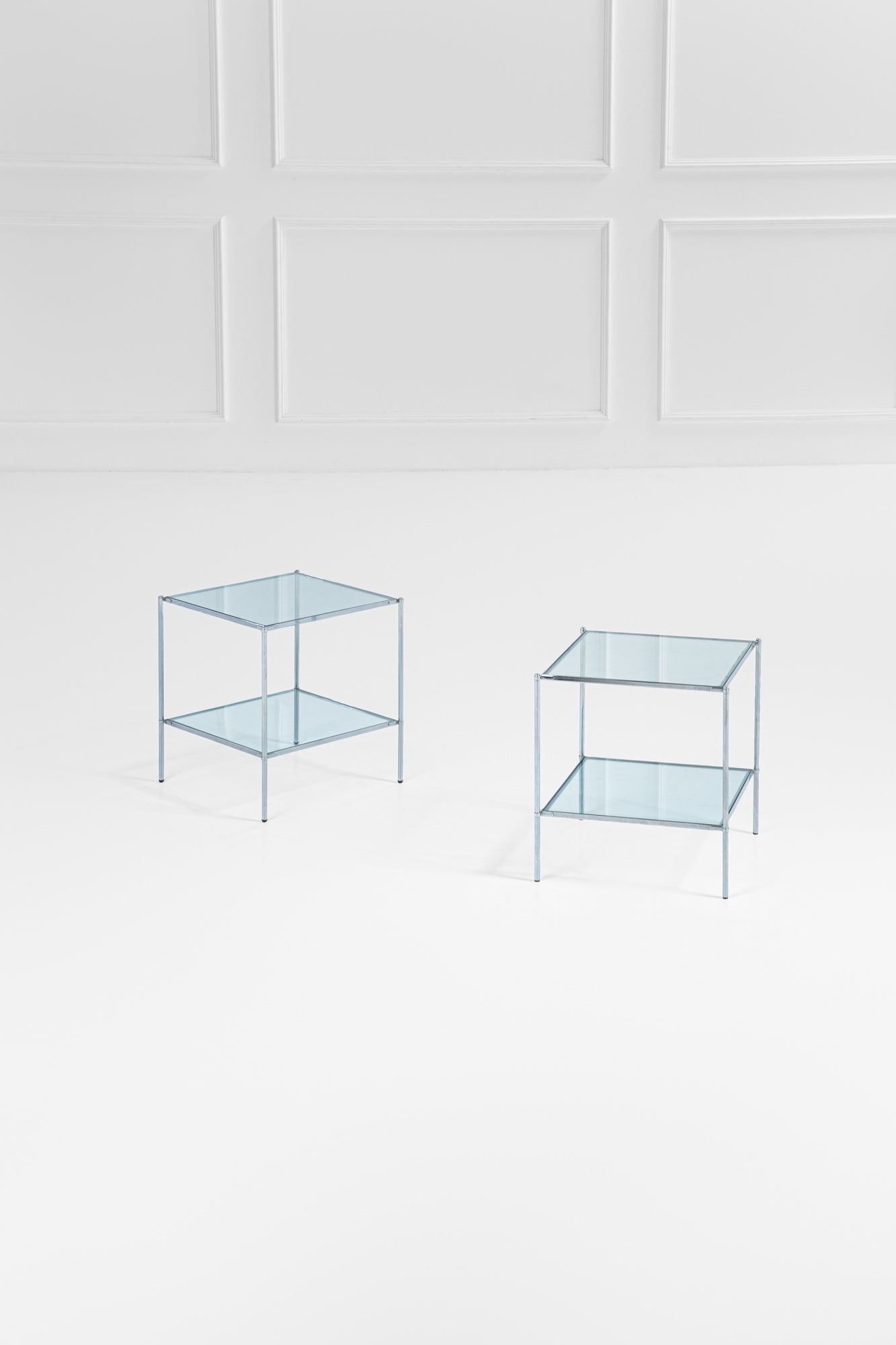 Due tavolini a due piani mod. T12: Due tavolini a due piani mod. T12 Metallo cromato, vetro. Prod. Azucena, 1970 ca. cm 46x42x42 BIBLIOGRAFIA: Catalogo Azucena.