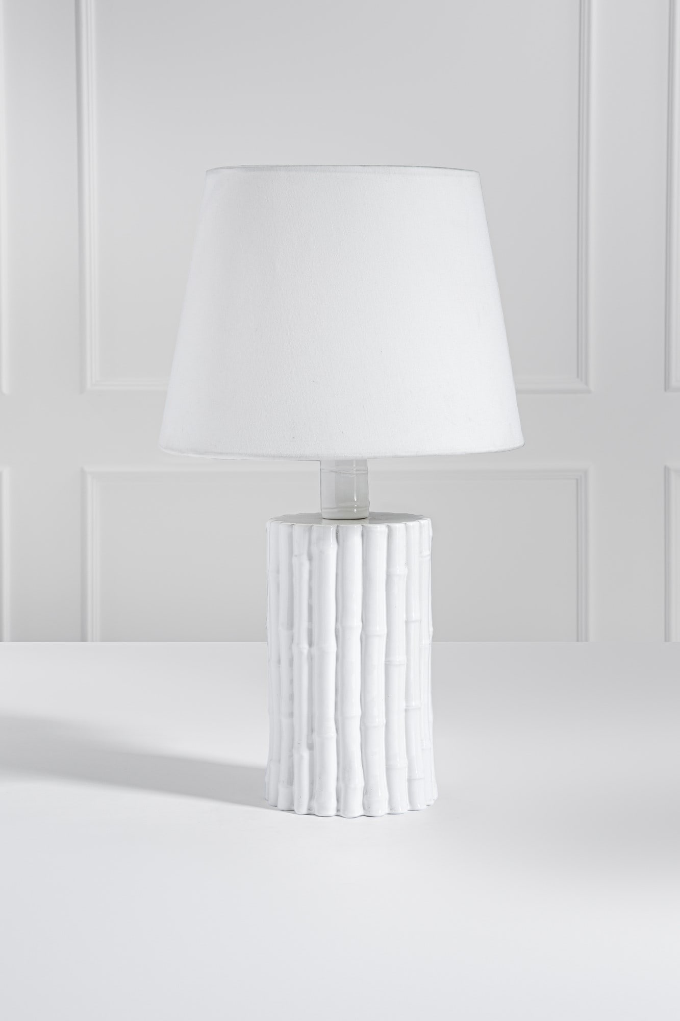 Lampada da tavolo: Lampada da tavolo Ceramica bianca ad imitazione delle canne di bamboo, tessuto. 1970 ca. h cm 72, diam. cm 41