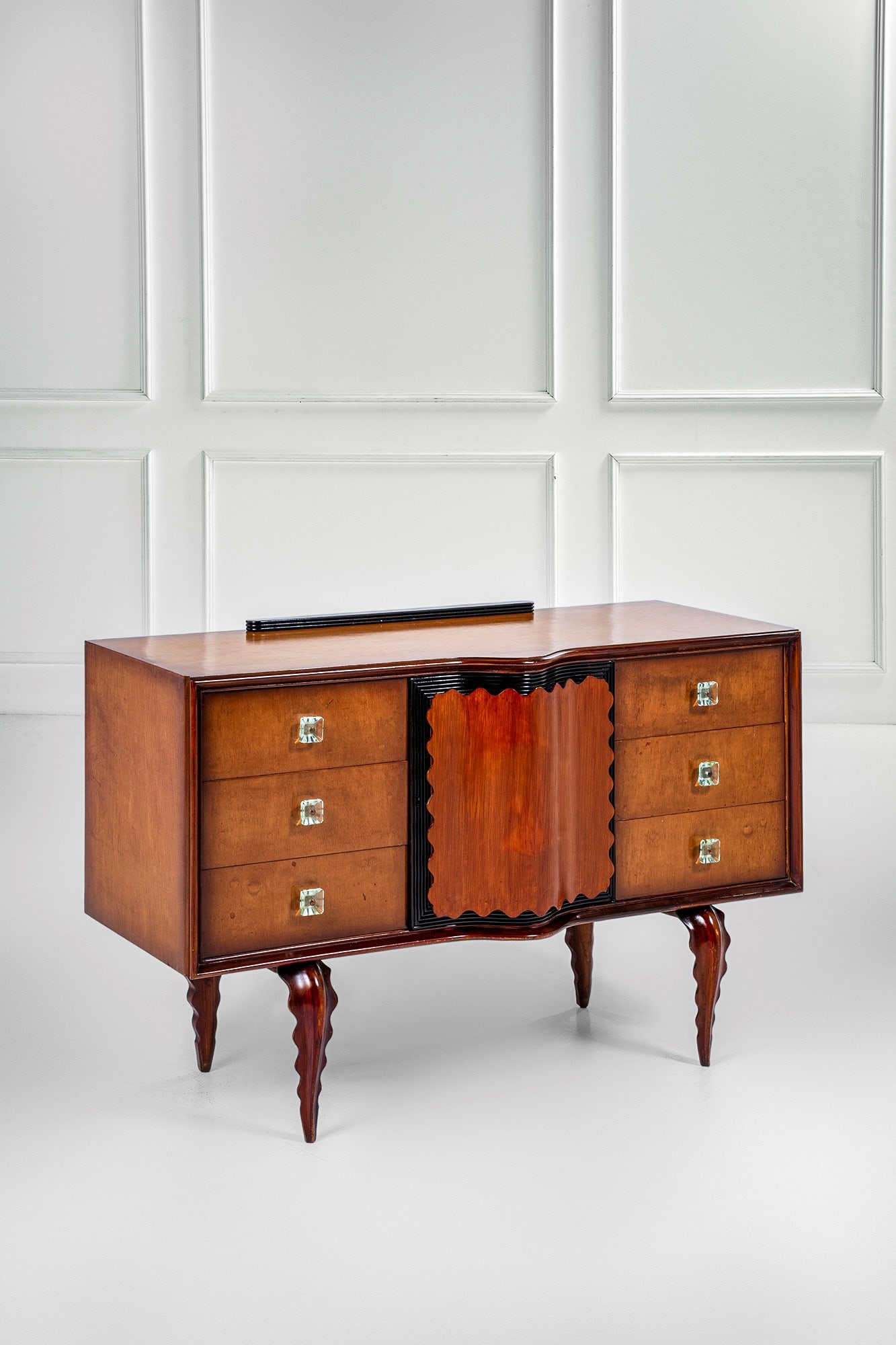 Mobile contenitore a due file di cassetti e anta centrale celante cassetti: Mobile contenitore a due file di cassetti e anta centrale celante cassettiLegno impiallacciato, radica, legno ebanizzato, legno massello sagomato, maniglie in cristallo molato verde Nilo, ottone.1940