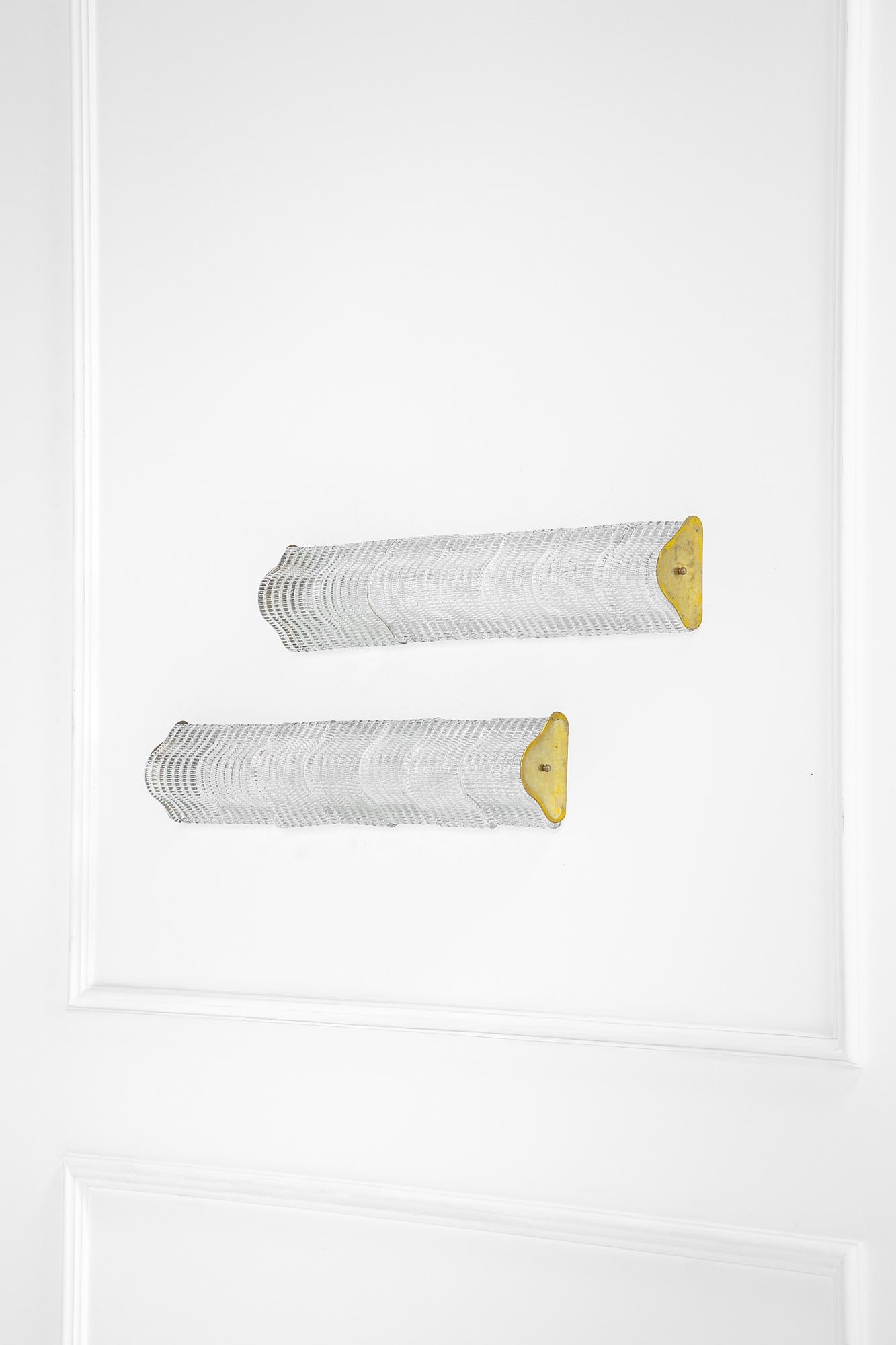 Carlo Scarpa. Due lampade da parete: Due lampade da parete Elementi sagomati in vetro bugnato, ottone. Prod. Venini, 1940 ca. cm 15x73x9 Bibliografia: Venini, Catalogo blu VI, profili sagomati.