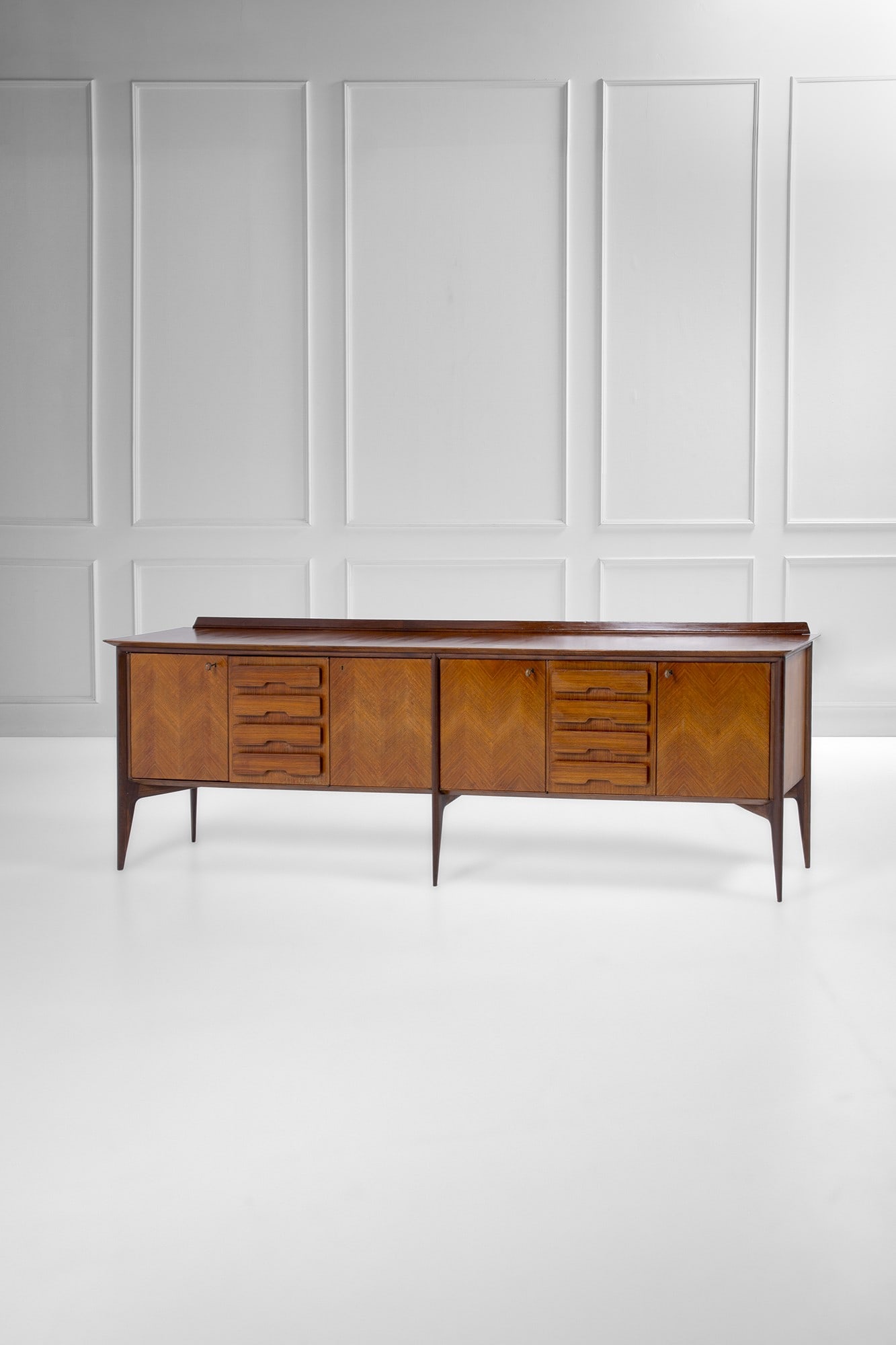 Ico Parisi. Credenza con falsi cassetti mod. 1948.5: Credenza con falsi cassetti mod. 1948.5 Legno tinto scuro, legno naturale, legno impiallacciato a spina di pesce. Mobili contenitori chiusi da tre ante, ottone. 1948 ca. cm 97x290x53 Bibliografia: R.