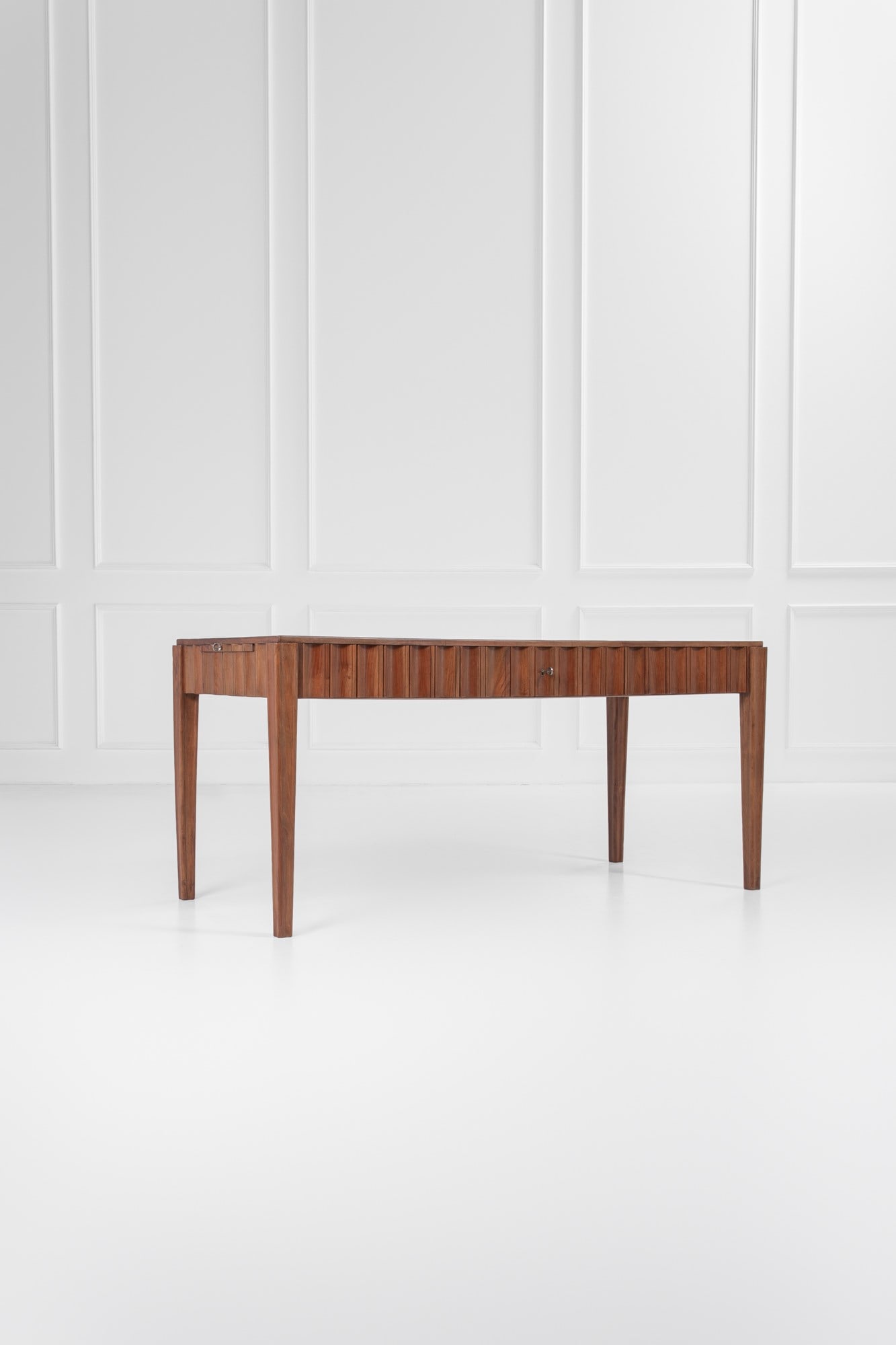 Paolo Buffa (attr.). Scrivania con cassetto centrale e pianetto estraibile laterale: Scrivania con cassetto centrale e pianetto estraibile laterale Legno scolpito a drappeggio, legno massello, legno impiallacciato. 1950 ca. cm 80x174x77