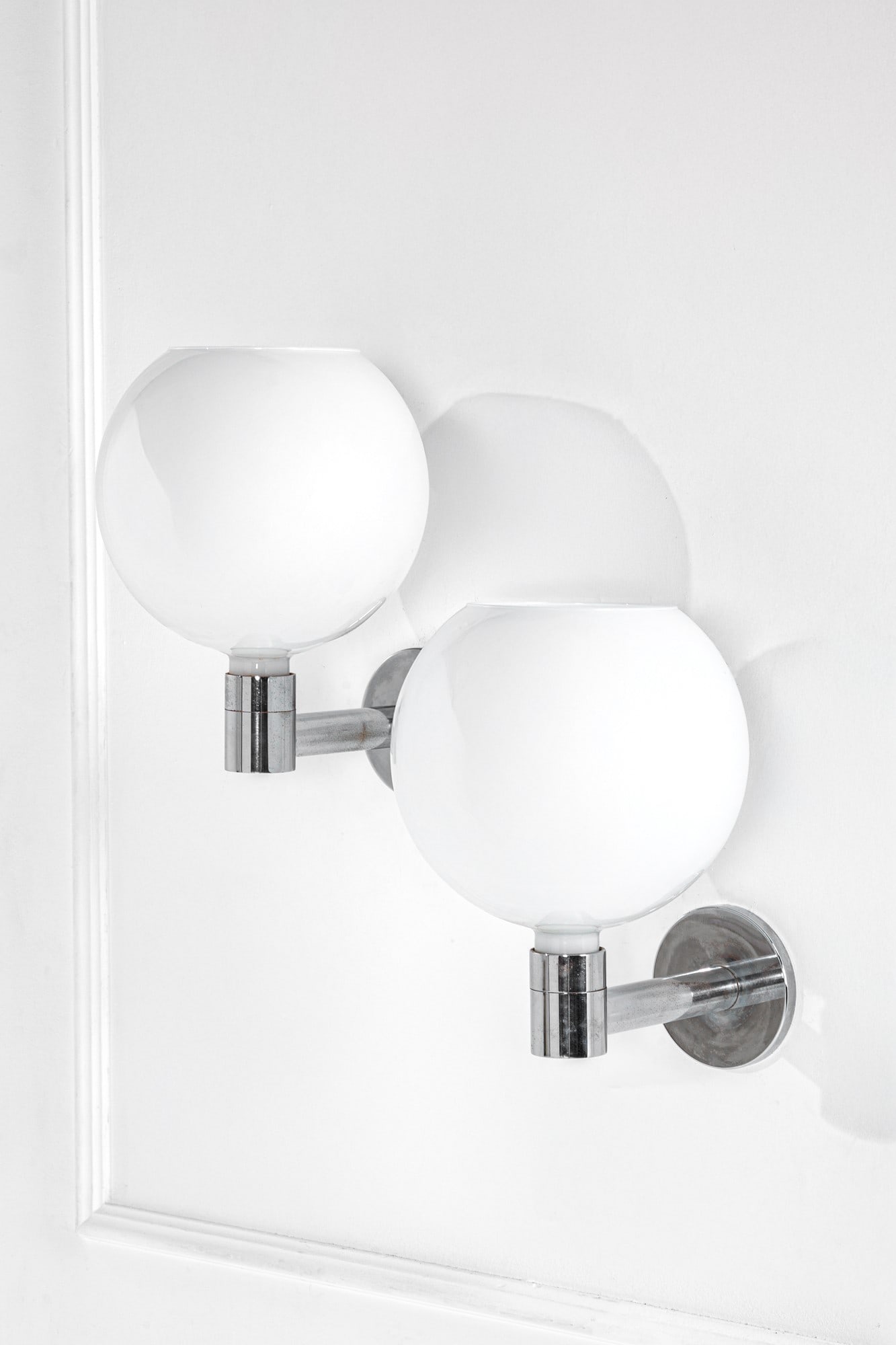 Franco Albini, Franca Helg, Antonio Piva. Due lampade da parete della serie AM/AS: Due lampade da parete della serie AM/AS Metallo cromato, vetro opalino. Prod. Sirrah, 1969 ca. Marchio del produttore. cm 43x29x38 Bibliografia: Domus n. 469, dicembre 1960, p. d/449.