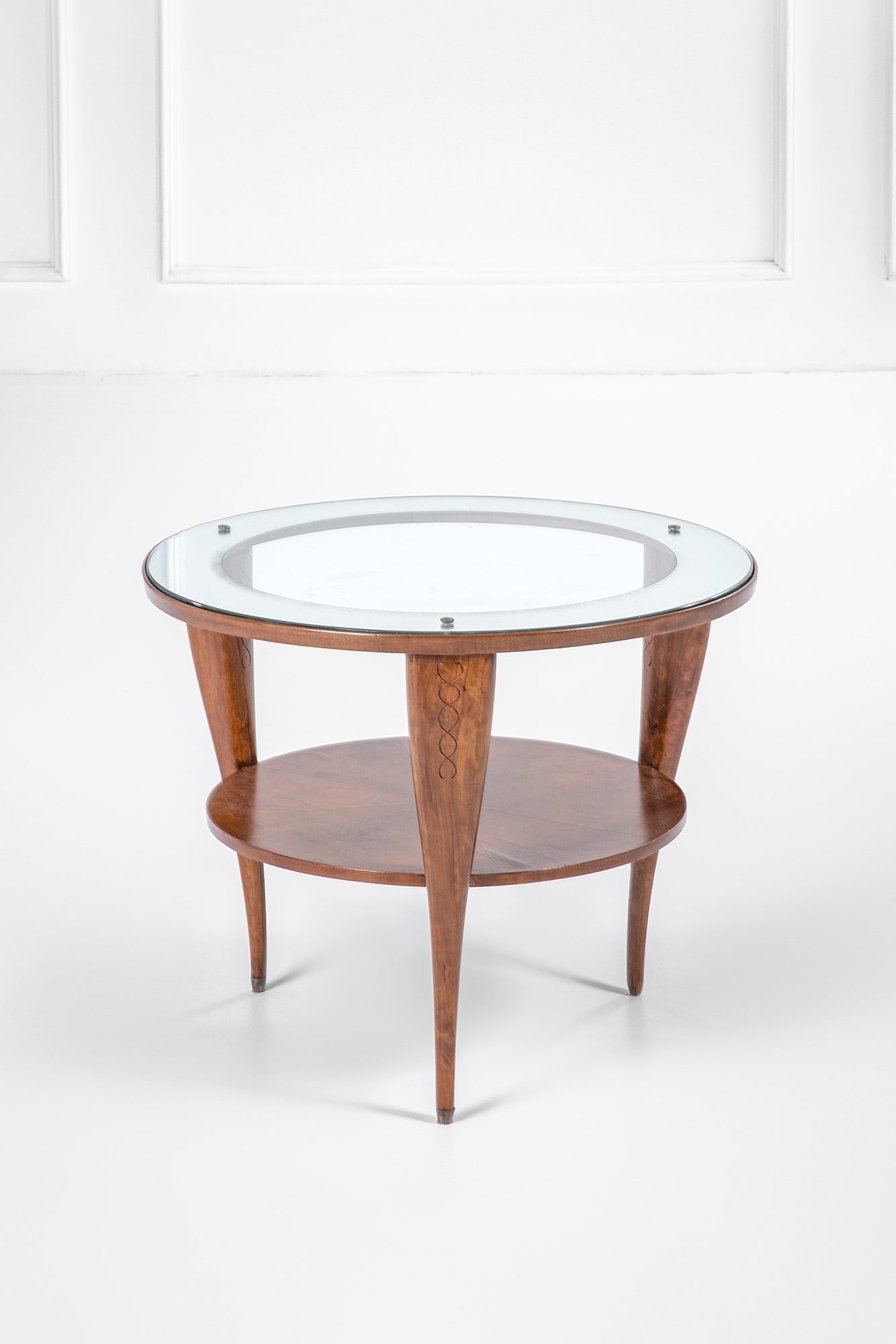 Tavolino: Tavolino Legno massello sagomato con decoro inciso, legno impiallacciato, vetro con fascia specchiata, ottone. 1950 ca. h cm 55, diam. cm 70