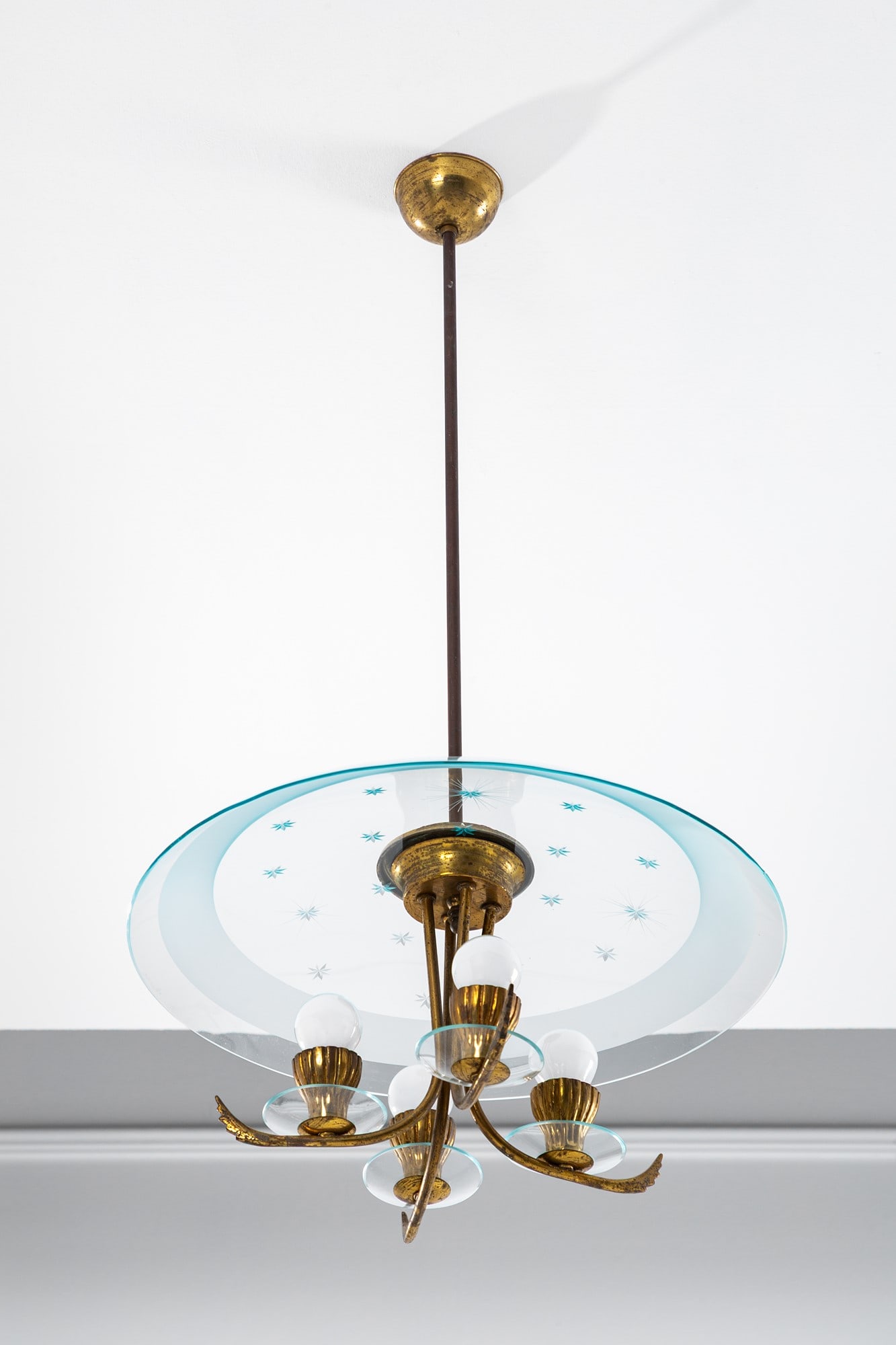 Lampadario a quattro luci: Lampadario a quattro luci Ottone lucido, vetro trasparente curvato con fascia satinata e decoro inciso a stelle, vetro trasparente. 1950 ca. h cm 83, diam. cm 45