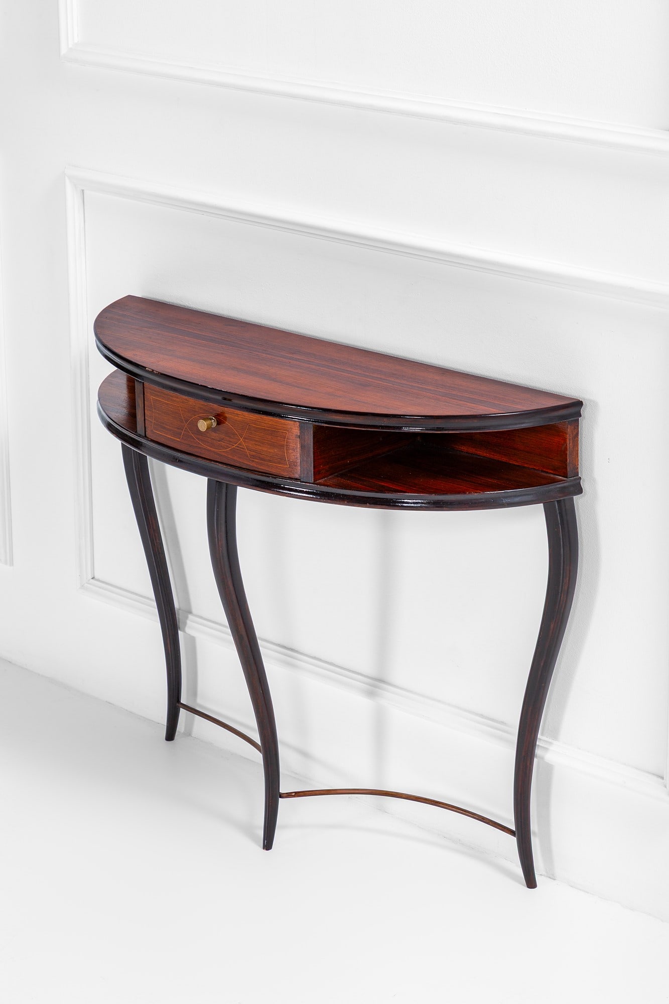 Console a mezzaluna: Console a mezzaluna Legno impiallacciato, legno tinto, ottone, decoro intarsiato sul cassetto. 1950 ca. cm 85x112x34