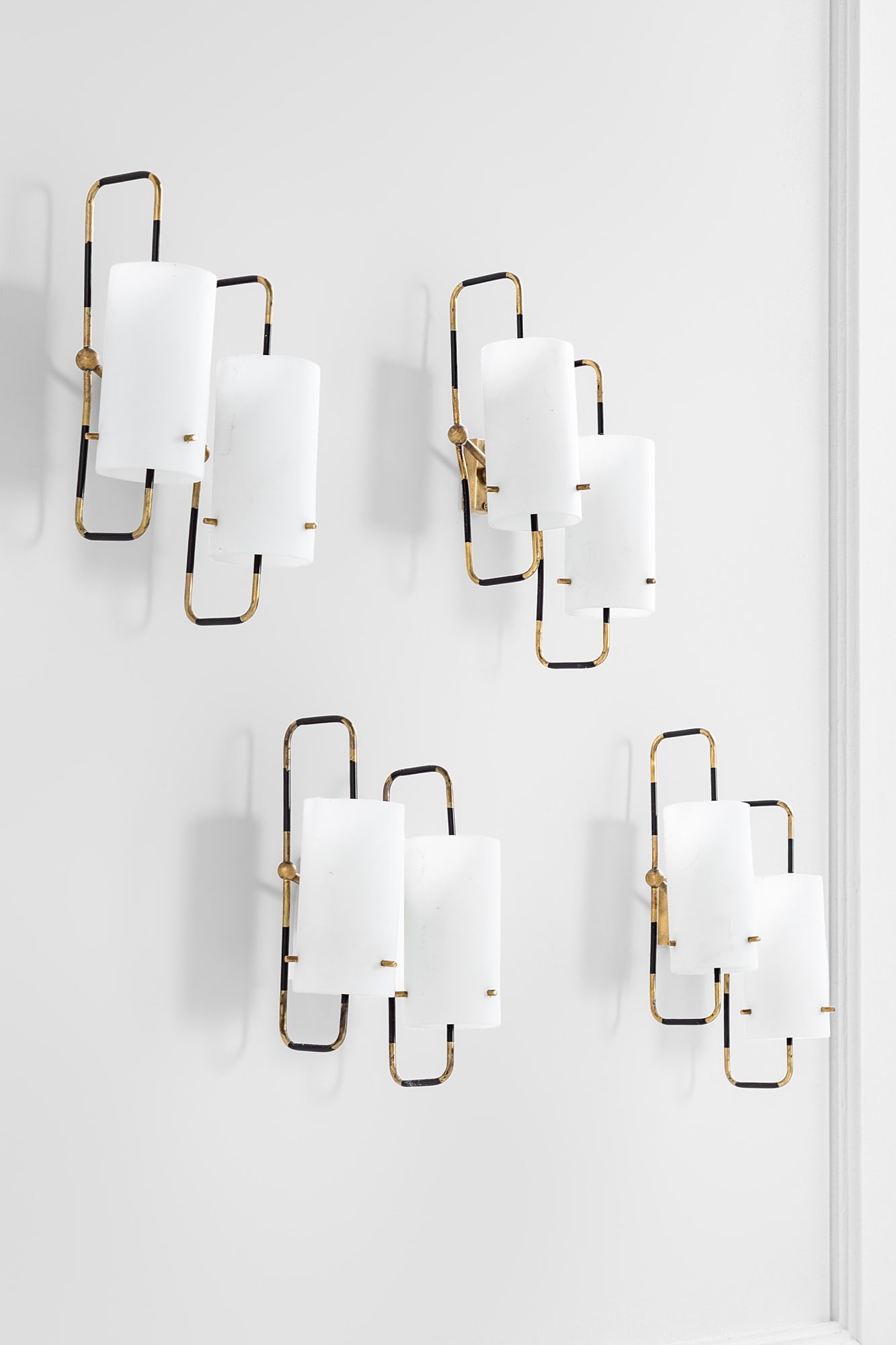 Stilnovo (attr.). Quattro lampade da parete a due luci: Quattro lampade da parete a due luci Ottone, metallo verniciato, vetro opalino satinato. 1950 ca. cm 15x31x13