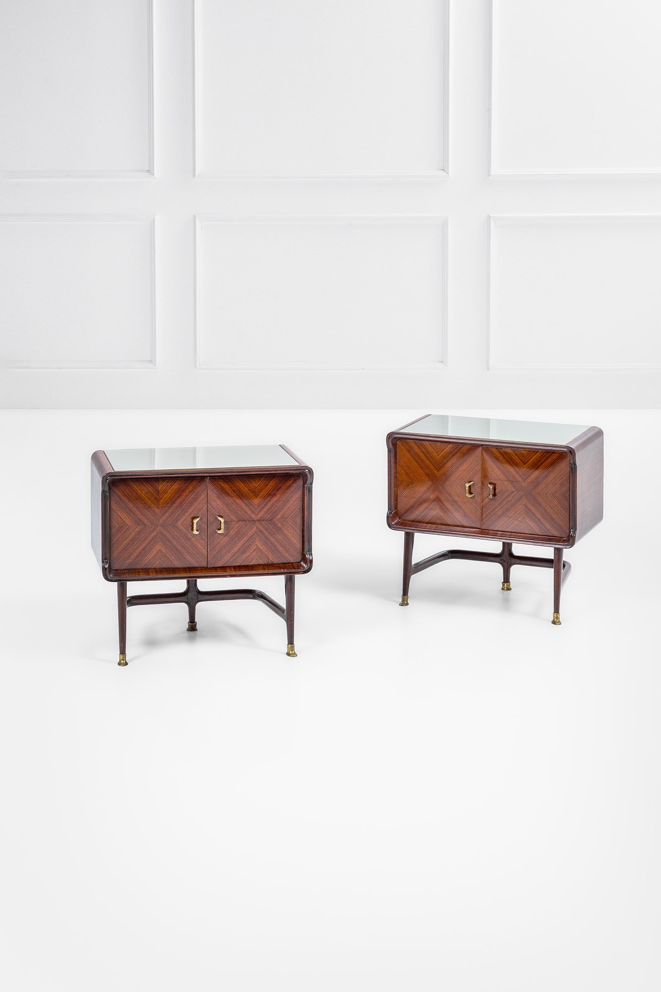 Carlo De Carli, nel gusto di. Due comodini: Due comodini Legno impiallacciato, legno massello sagomato e tinto, ottone, vetro specchiato. 1950 ca. cm 59x65x36